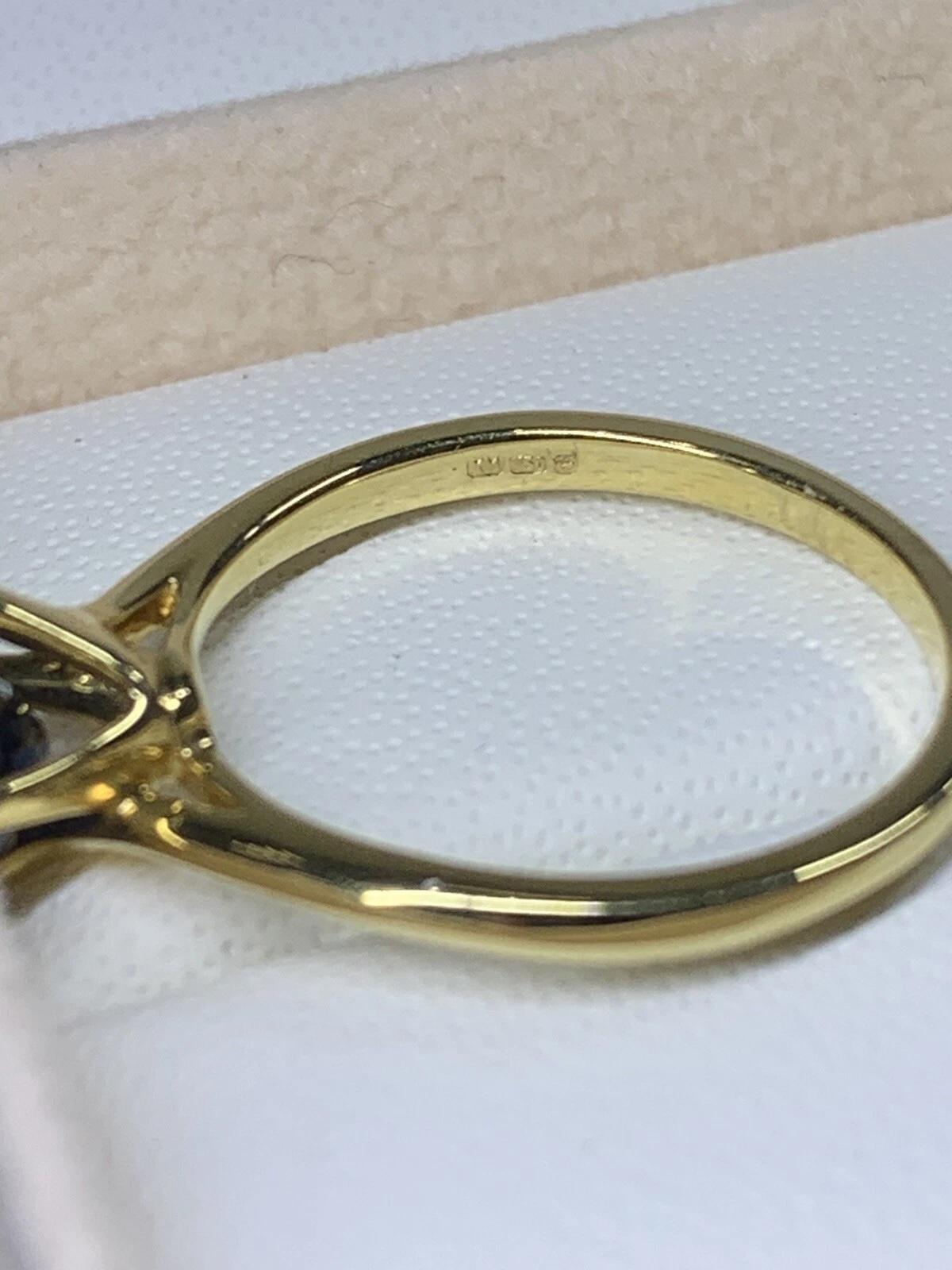 Faites une déclaration d'amour audacieuse avec cette bague de fiançailles solitaire en saphir de Ceylan de 0,92ct. Réalisée en or jaune 18 carats, cette bague est ornée d'un saphir de forme ovale en guise de pièce maîtresse. Le style de sertissage