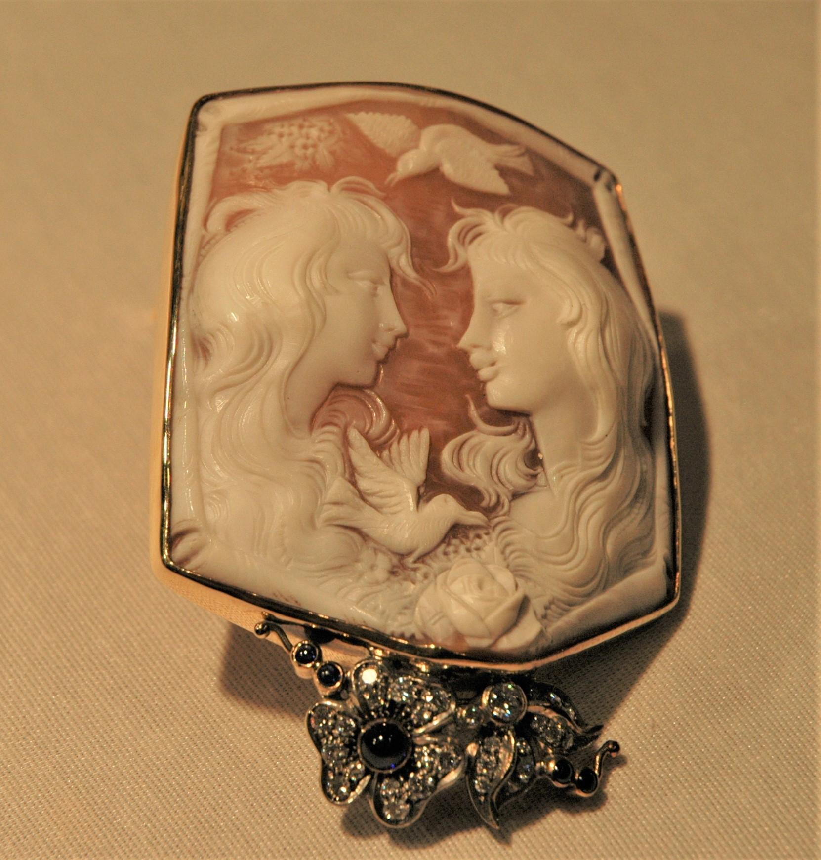 This is a very special cameo brooch, handmade in Italy. It represents two women, the one in front of the other, located in a bucolic setting: there are some flowers and two birds. The manufacturing of the cameos is a typical processing of Torre del