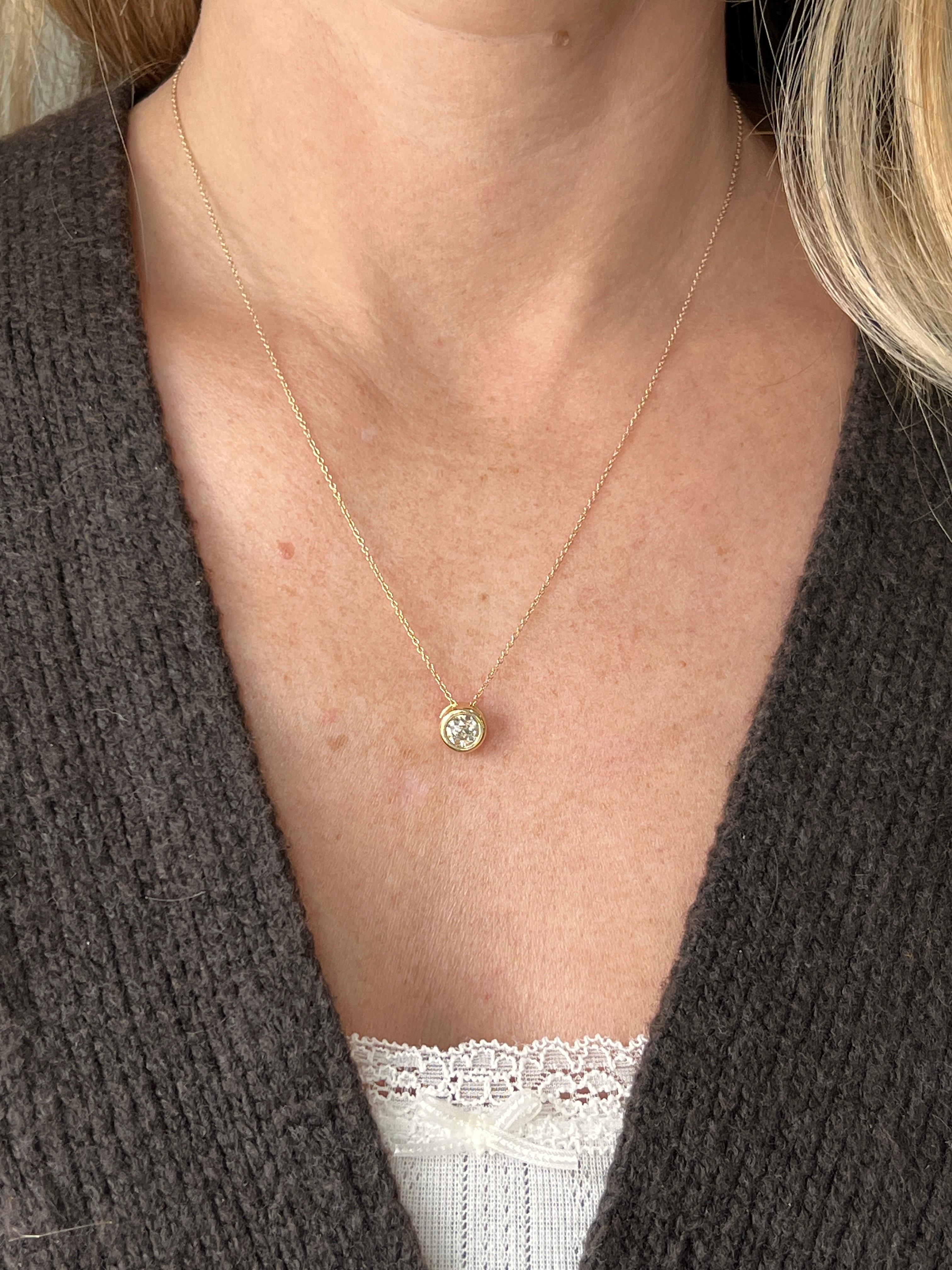 Un collier pendentif contemporain en or jaune 14 carats comportant un diamant de taille européenne ancienne serti en chaton pesant environ 0,945 carats de couleur L et de pureté I1, montrant une légère fluorescence bleue. Le pendentif est suspendu à