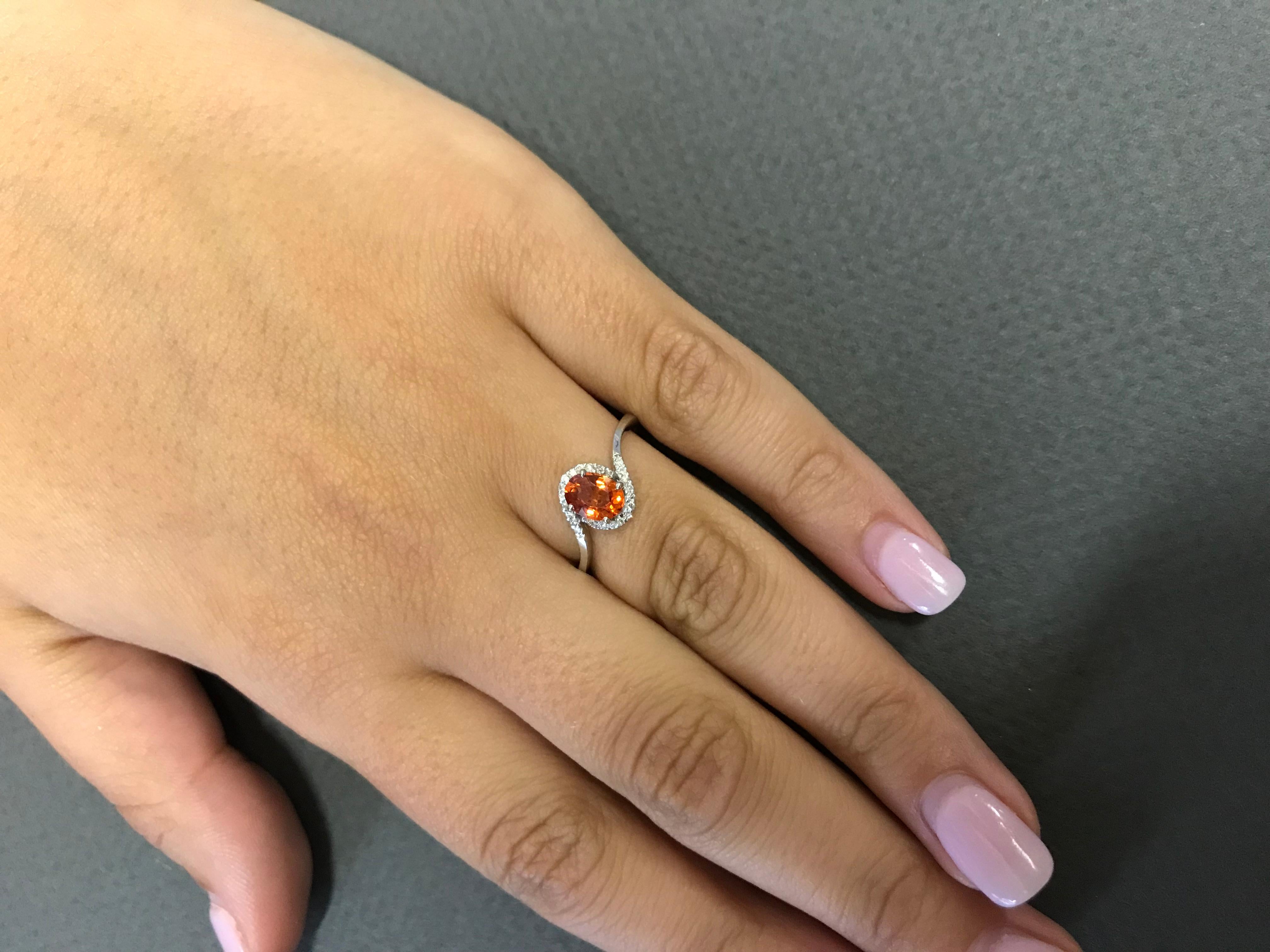 Material: 14k White Gold 
Color Stone Details:  0.95 Carat Oval Cut Orange Sapphire 
Center Stone Details: 24 Brilliant Round White Diamonds at 0.11 Carats Clarity: SI  / Color: H-I
Ring Size: Size 6.75 (can be sized)

Fine one-of-a kind