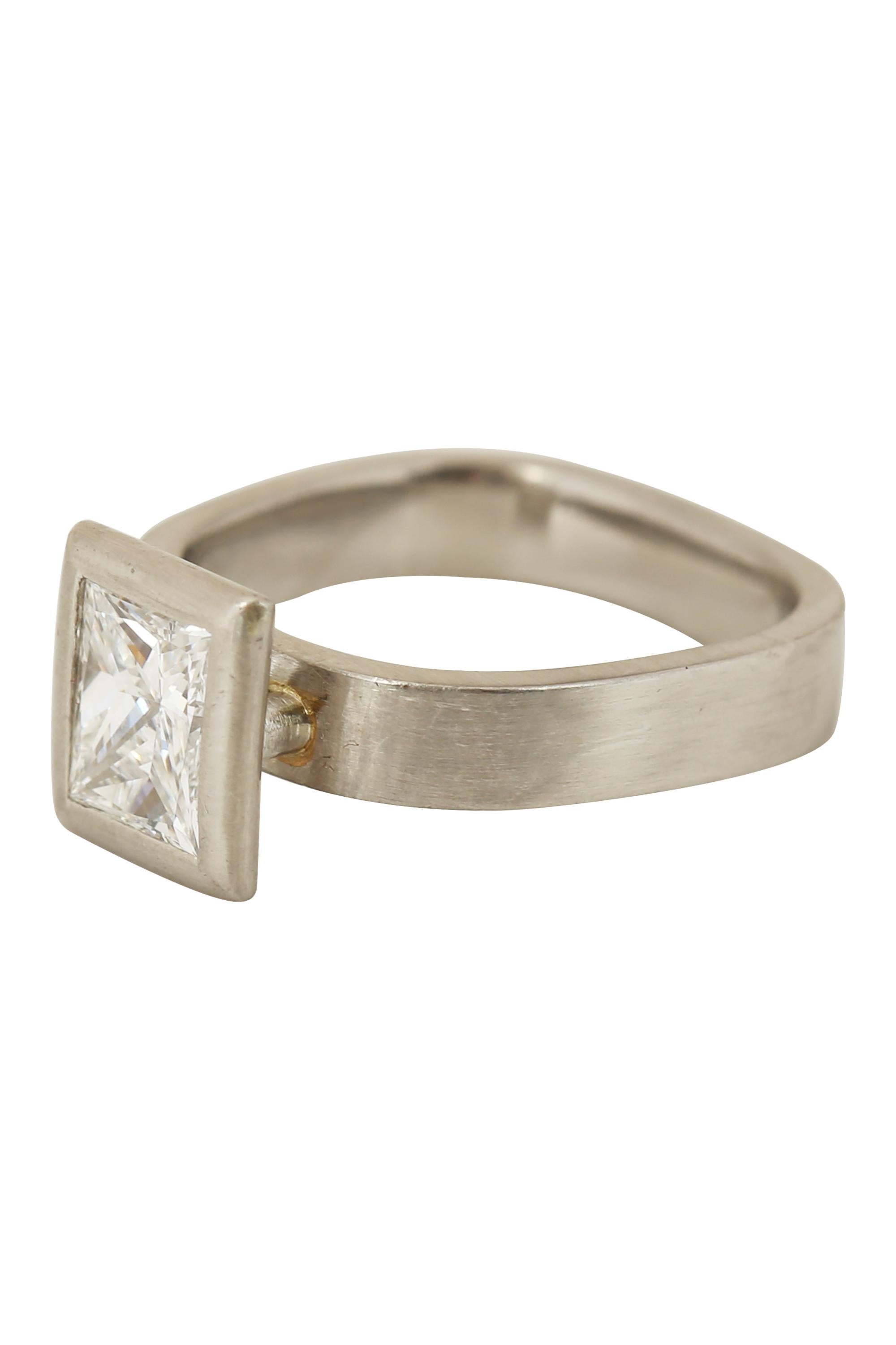 A 0.95 carat princess cut diamond with G color and VS1 clarity radiates from within a modern framing of brushed platinum surmounting a modern geometric ring. Currently Size 4. 

