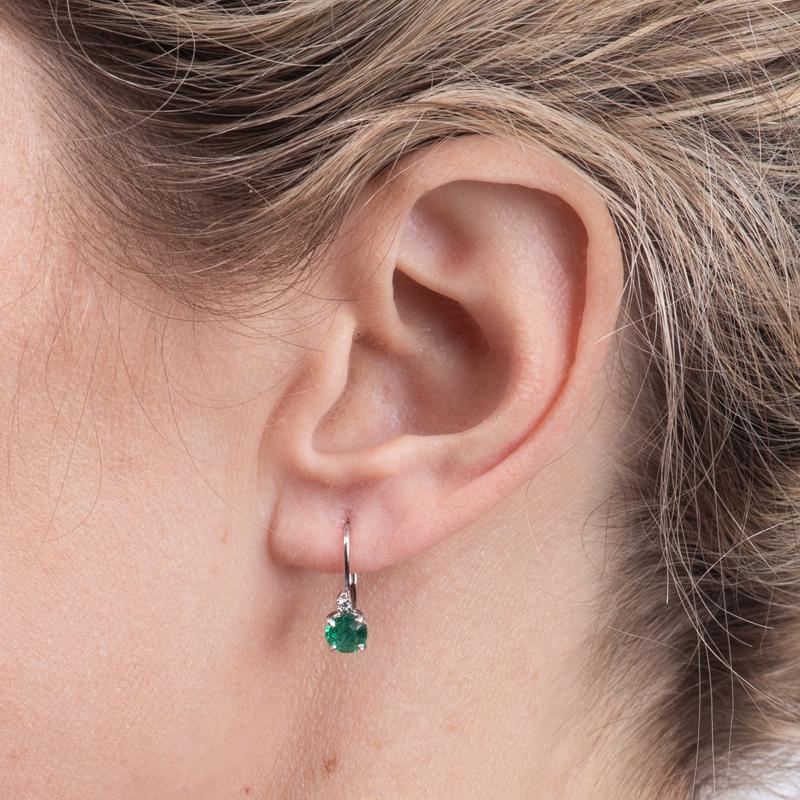 These petite earrings feature beautiful natural round emeralds with a total carat weight of 0.95 carats set in 14 karat white gold with two small diamond accents. Lever back. These are a great everyday earring with a little pizazz.