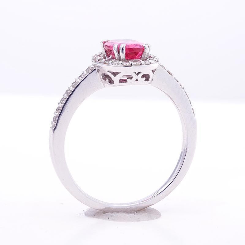 Deep, neon pink, this Spinel from Tanzania weighs 0.98 carats and has an irreplaceable color. Set within strong 14K white gold prongs, this ring will highlight any skin tone. A crown with 0.22 carats of diamonds surrounds the center spinel bringing