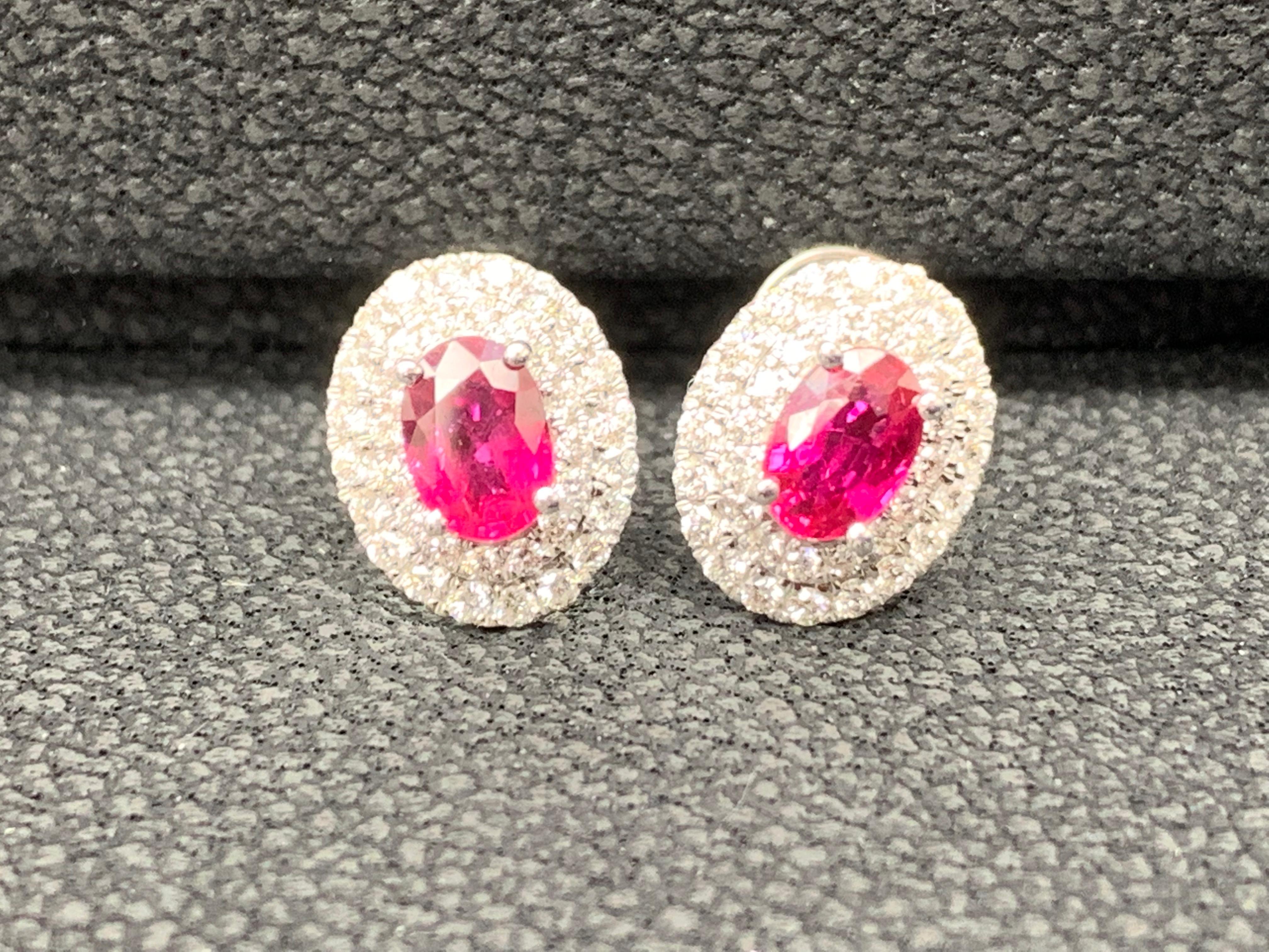 A simple pair of stud earrings showcasing 0.98 carats of oval cut red rubies, surrounded by a double row of 72 round brilliant diamonds weighing 0.48 carat. Made in 18 karat white gold.