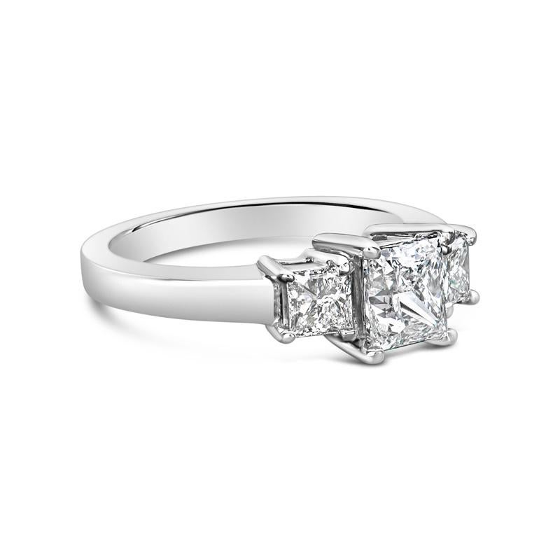 This three stone engagement ring features a 0.98 carat princess cut natural diamond, G SI1, accented by 0.50 carat total weight in two princess cut side diamonds set in 14 karat white gold. This ring is currently a size 4.75 but can be resized upon