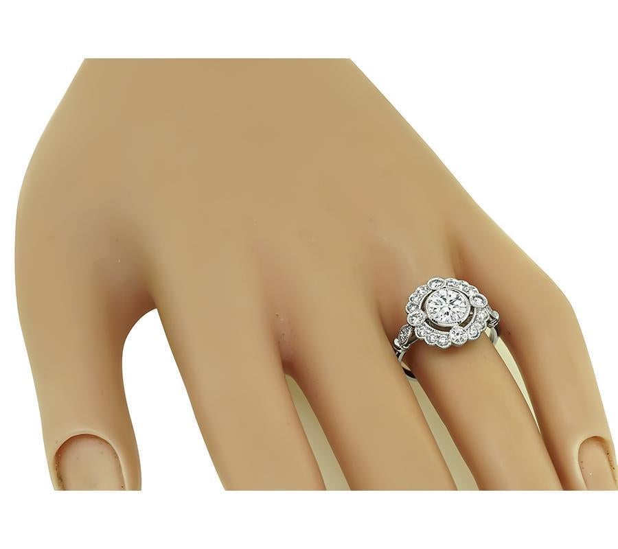 This is an elegant platinum engagement ring. The ring is centered with sparkling round cut diamond that weighs approximately 0.98ct. The color of the diamond is F with VS clarity. The center diamond is accentuated by dazzling round and cut diamonds