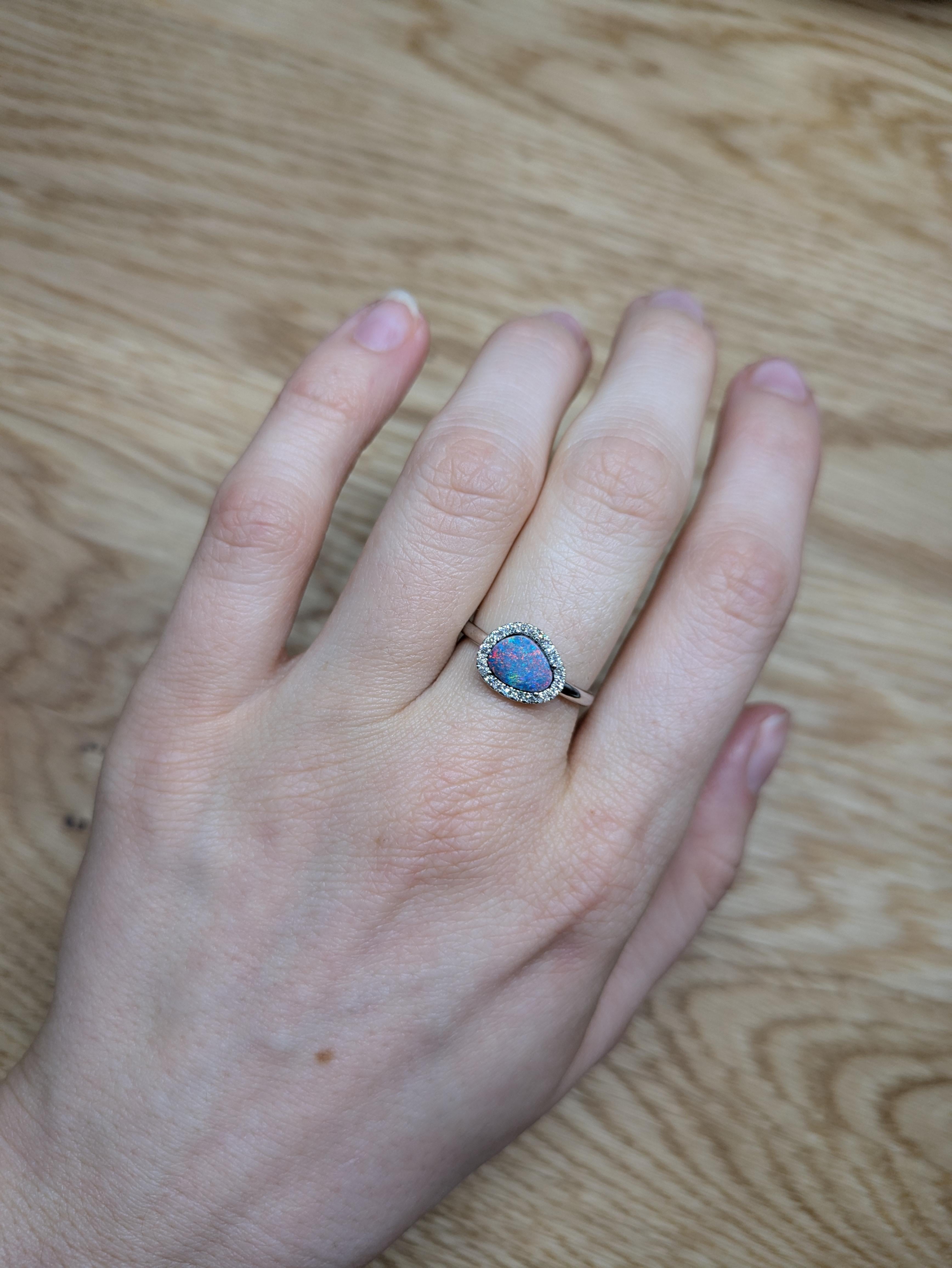 Der Ring aus 14-karätigem Weißgold präsentiert einen fesselnden Boulder-Opal von 0,91 Karat, der für sein faszinierendes Farbenspiel bekannt ist, das von leuchtenden Blau- und Rosatönen bis hin zu sanftem Violett reicht. Der Opal ist elegant von