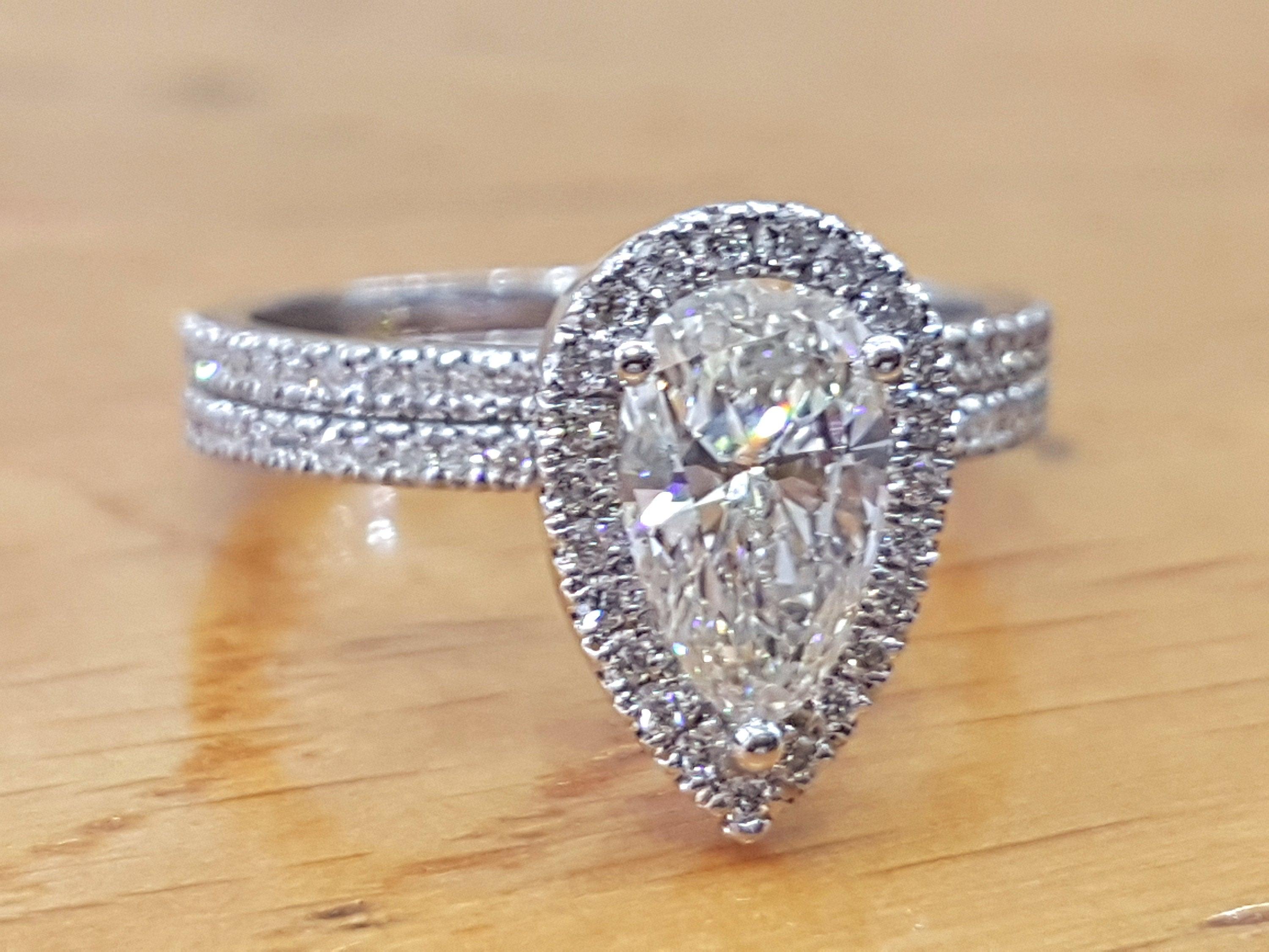 A beautiful diamond engagement ring set made of 14K White Gold set with a pear cut diamond of 1.00ct (can be set with any stone size) accented by white round diamonds. The center diamond of this classic gold ring is a natural SI1 clarity and H
