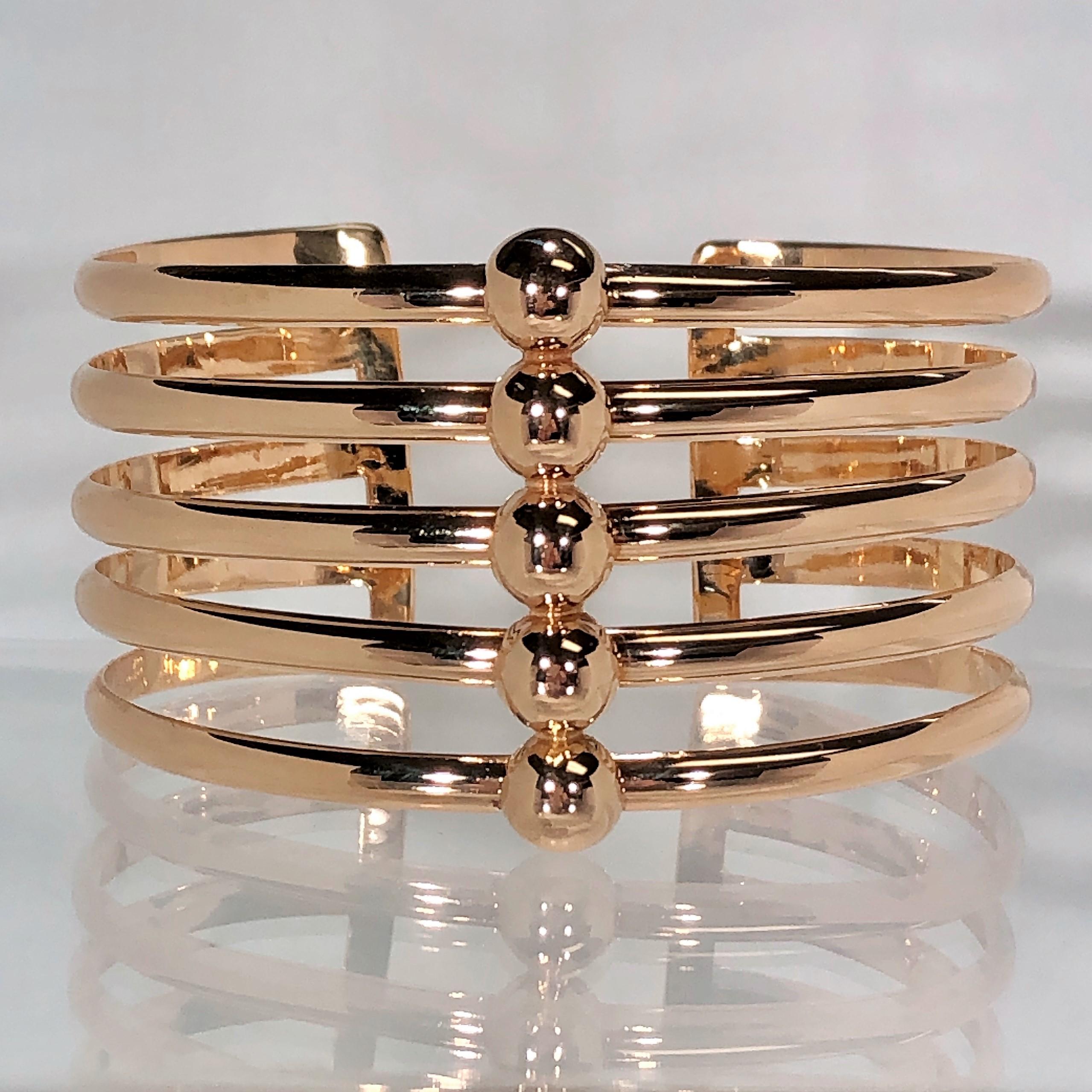 This stylish, oval shaped Retro cuff is fashioned in 14k rose gold. The five open rows measure 1  1/2 inches at 
the widest point in front, and taper down to 1  5/16 inch. The cuff slides on and off with the open back.  Fits a 
small to medium size