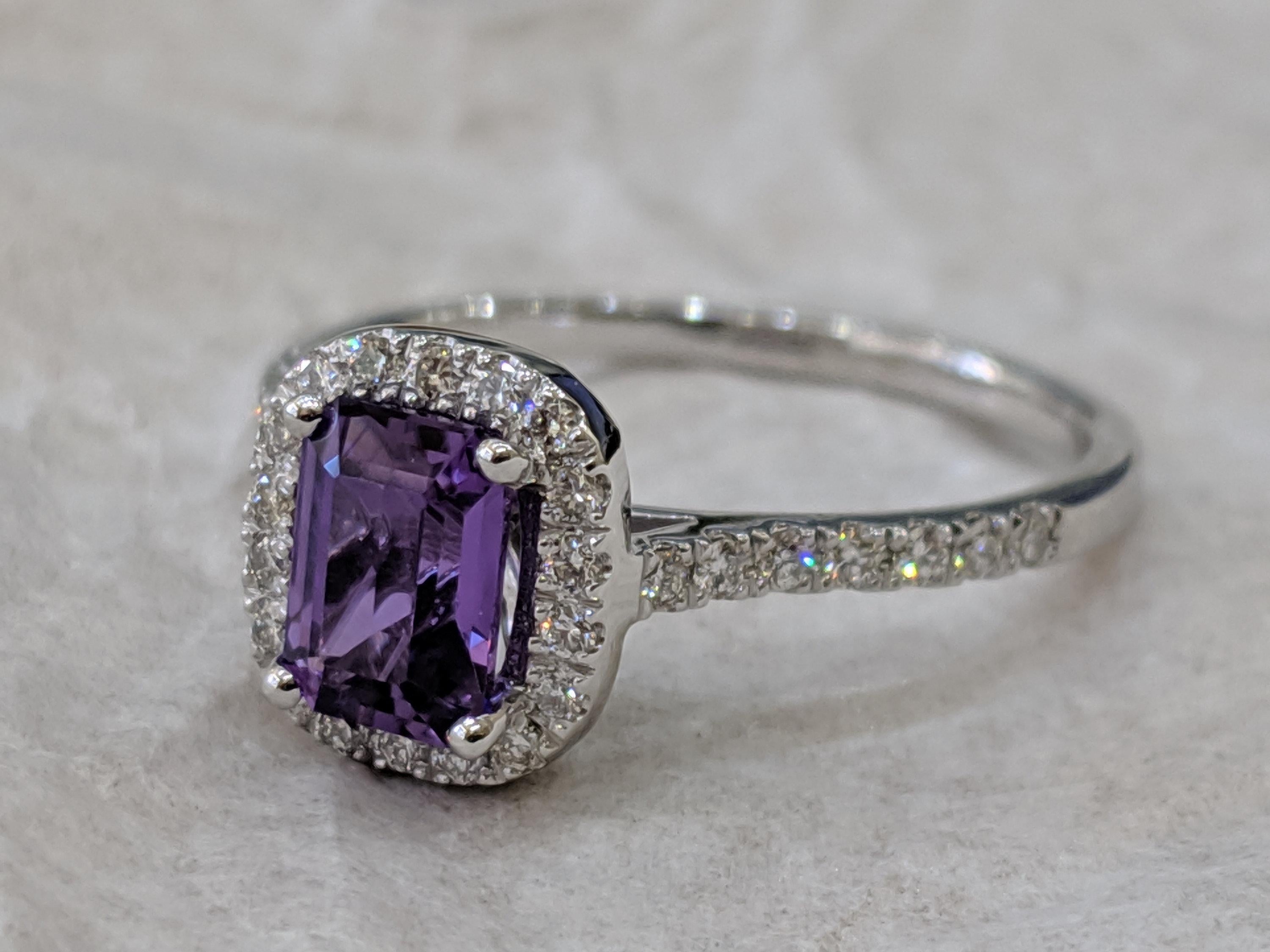 This contemporary Purple Sapphire ring is made of 14k white gold with Emerald -cut central Sapphire of 1.25 carats with Violet natural color, gently holded by prongs above a circle of small white diamonds, making this jewelry unique. This high