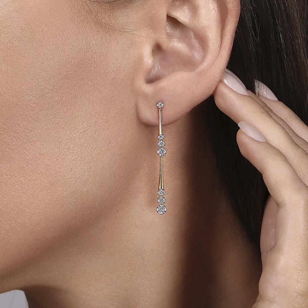 These sleek Gabriel & Co. earrings are stunning! The yellow gold forms slender lines that flare out to wrap around graduated diamonds, then repeats with even larger diamonds! The lower drop has a hidden hinge to give the earrings a little extra
