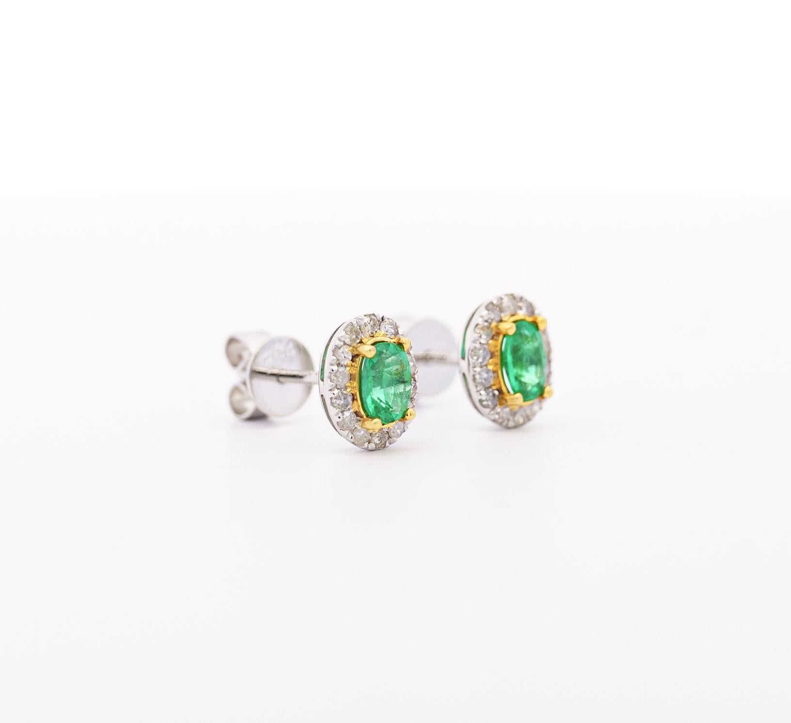 18k solid white and yellow gold oval shape and cut natural emerald and diamond halo stud earrings. Featuring natural oval cut emeralds with a strong green saturation and excellent transparency. The round diamond halo shimmers with brilliance as they