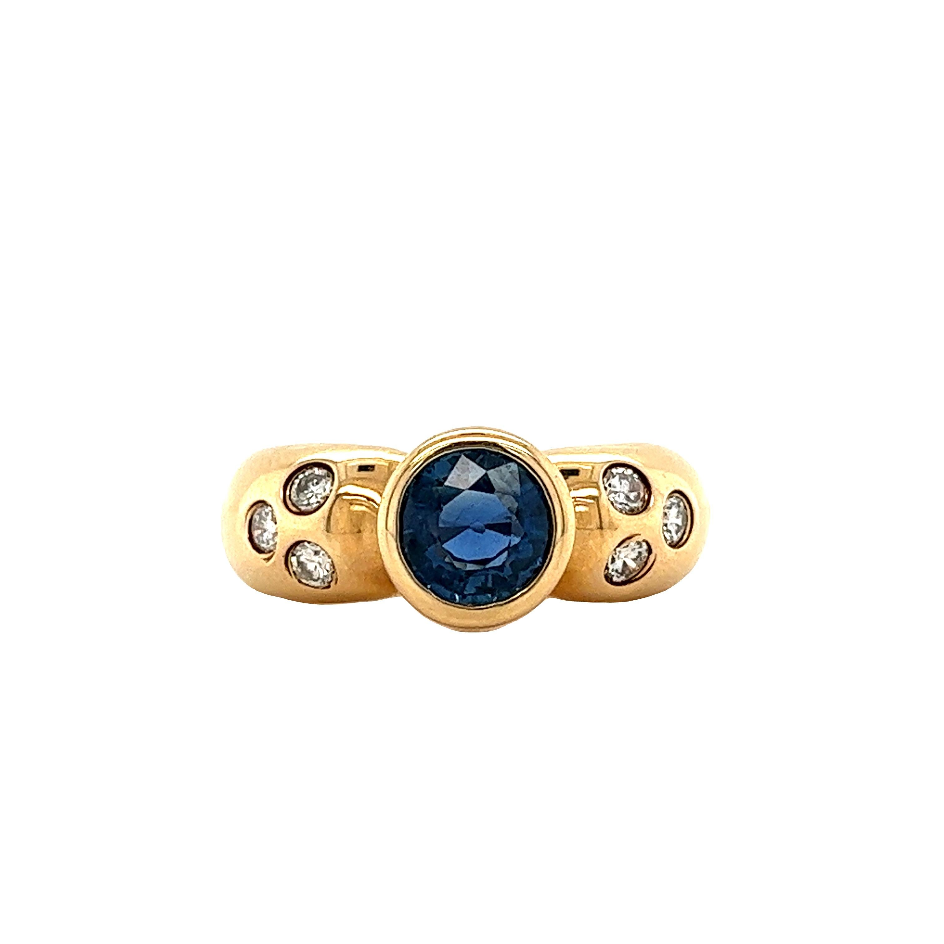 1.08 carat natural round-cut Blue Sapphire set with 0.12 carats in round-cut natural diamonds. The Blue Sapphire is mounted in an 14k yellow gold bezel setting with bezel set diamonds. The bezel setting provides excellent color contrast to the