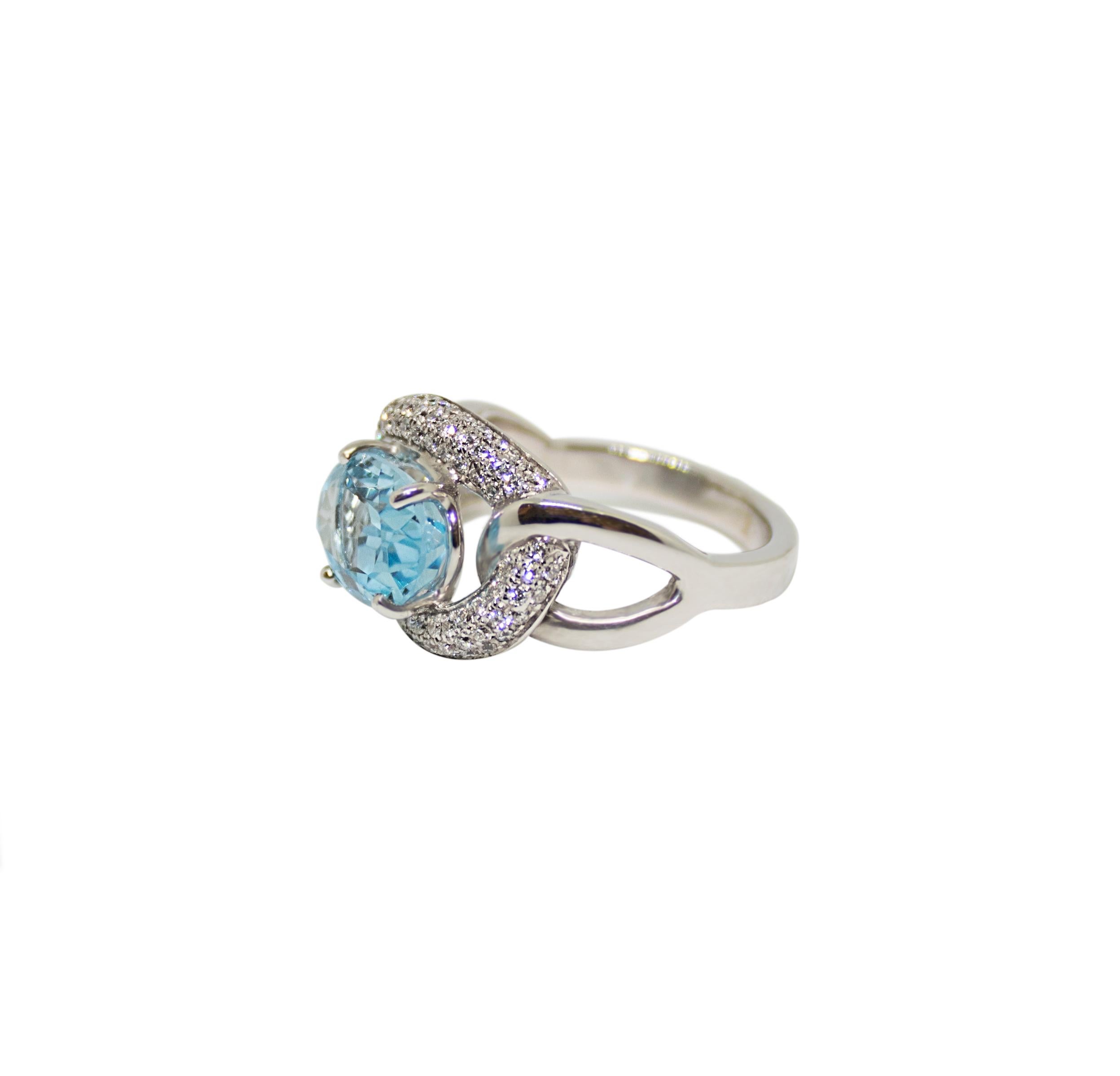 This ring features a 1 carat blue topaz centre stone, surrounded by a diamond halo and mounted in four claw clasp to an 18 carat white gold engagement ring.  It is ideal as an engagement ring or as a cocktail ring and because it is a bespoke piece,