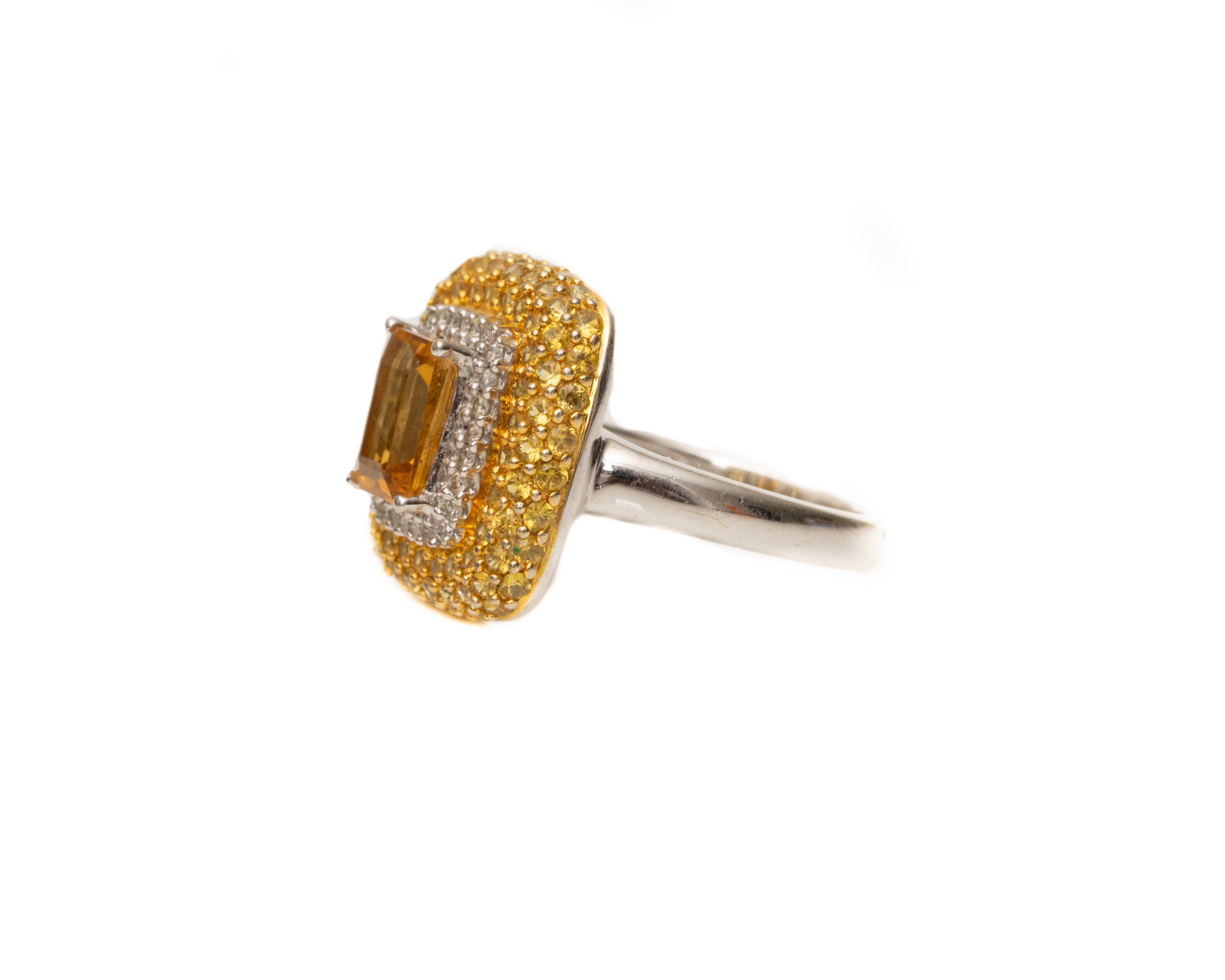Ring Details:
Metal type: 18 Karat White Gold
Ring Size: 6.5 (resizable)
Weight: 7.78 grams

Features:
1 Carat Citrine int he center, prong set and emerald cut
1 Carat Total of Yellow Sapphires, all round cut and prong set. These make up the outer 3