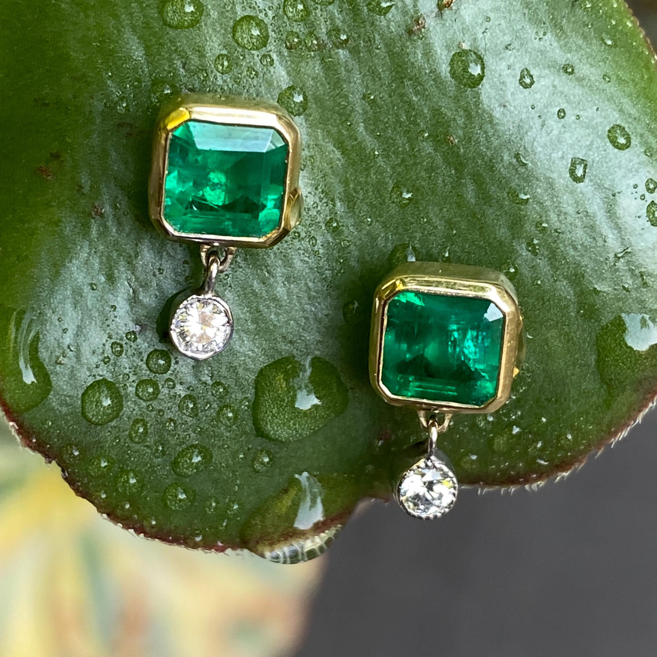 These gorgeous earrings by Eytan Brandes feature two natural Colombian emeralds wrapped in bezels of 18 karat yellow gold with a couple of bright little diamonds swinging along for the ride.

The emeralds are cut corner squares (emerald cut