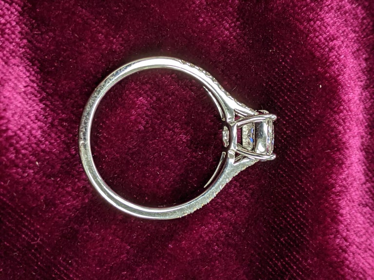 1.05 ct Cushion cut with E color and SI-1 clarity (GIA certificate upon request), is mounted on a solitaire made with not one, but two shanks.  This 18kt white gold mounting also has 40 small diamonds (0.23 ct) lining the front of the ring.

Crafted