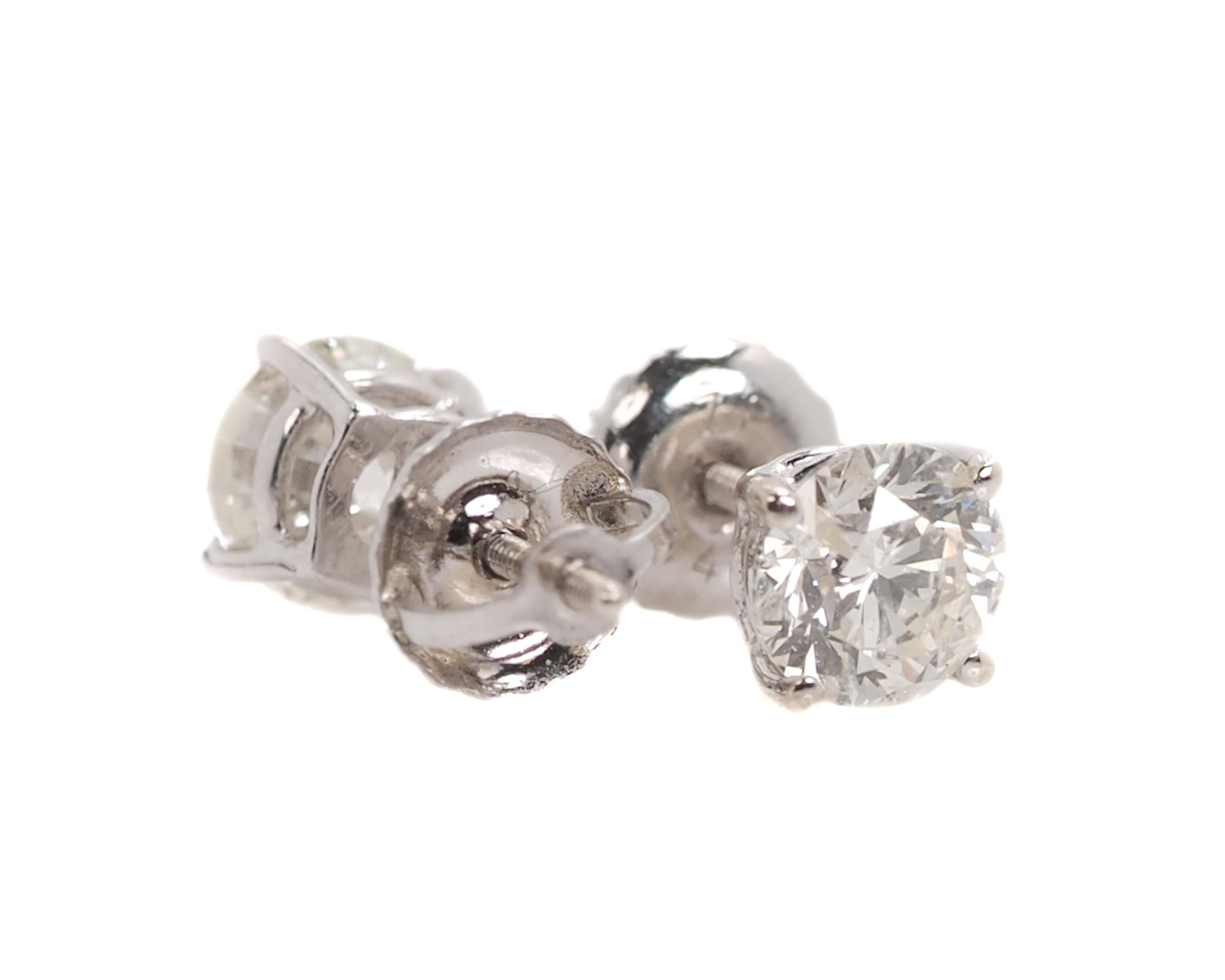 Made in-house, these screw back Diamond Stud Earrings are brand new. 
Each earring features a 0.5 carat Round Brilliant Diamond, totaling 1 Carat. 

The Diamonds are securely set in a 4-prong 14k White Gold frame. 
A simple gallery underneath