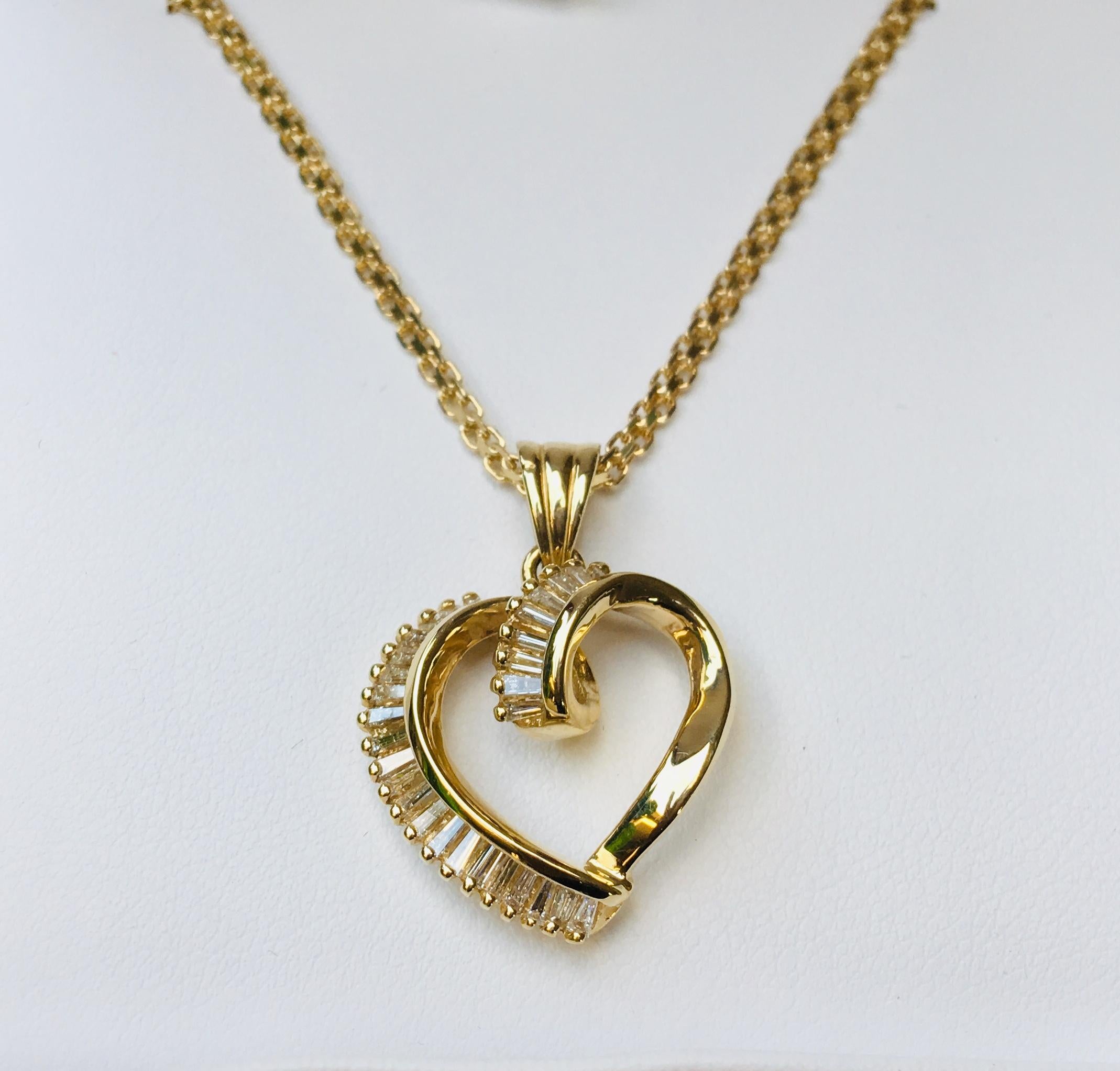 Lovely 14 karat yellow gold pendant features 30 sparkling diamond baguettes accenting a swirling ribbon of gold which forms a 3 dimensional heart.

Baguette diamonds measure 2.2 mm x 1 mm and weigh approximately 1 carat total diamond weight.

Face