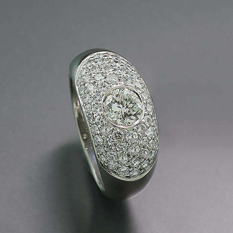 Un diamante solitario talla brillante de aproximadamente 1,02 quilates, color: Cristal, claridad: VS. La amplia cabeza del anillo, ligeramente abombada, está engastada con diamantes que suman aproximadamente 1,22 quilates, color del diamante: