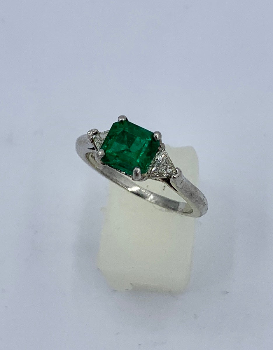 This is a stunning antique Emerald and Trillion Cut Diamond three stone ring in Platinum.  The Wedding Engagement Ring features an absolutely gorgeous Emerald Cut 1.16 Carat Emerald.  This Emerald is Deep Fine Green with superb clarity.  The Emerald