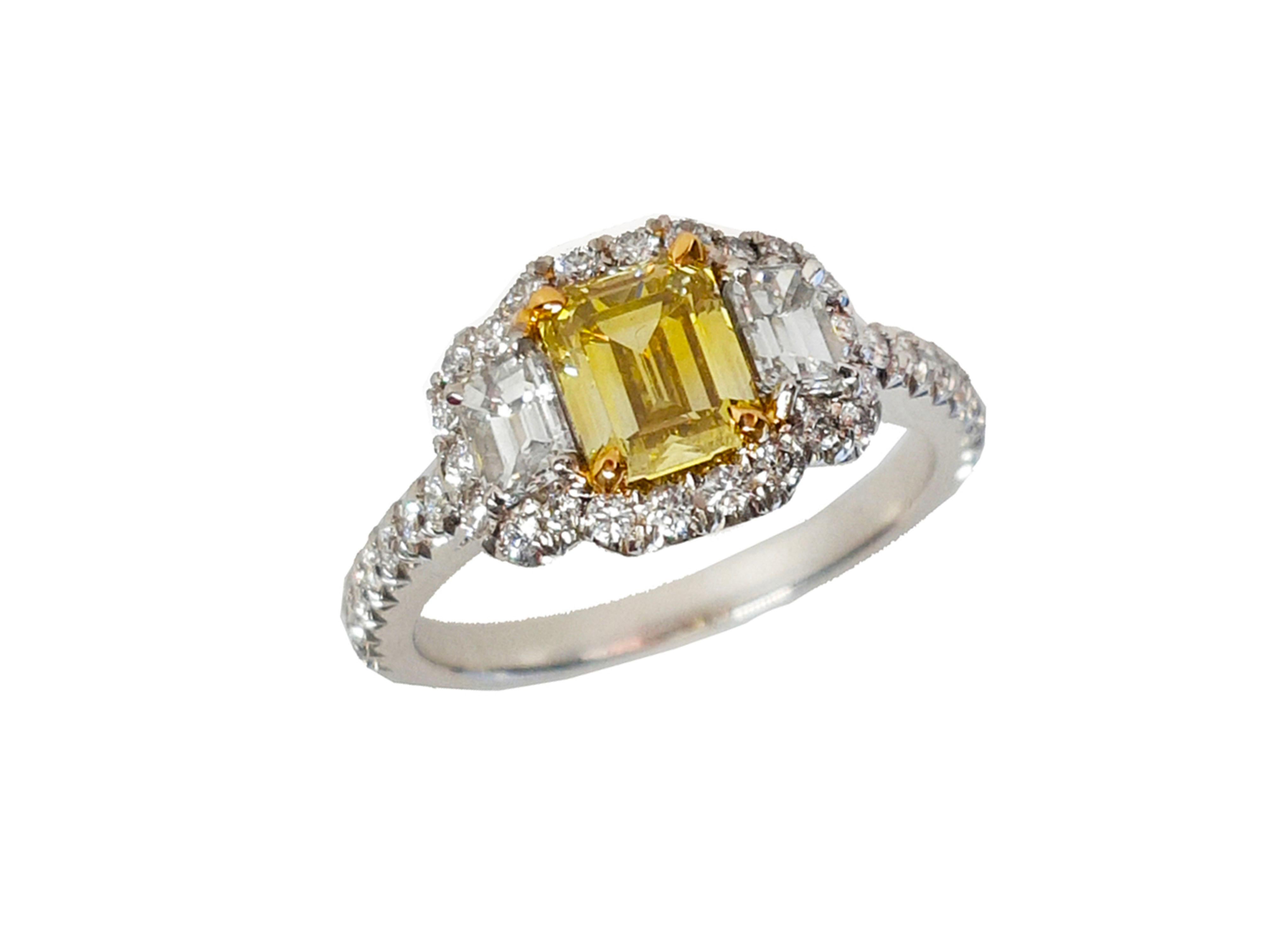 Ein atemberaubender Drei-Steine-Verlobungsring, 1,01 Karat Fancy Intense Yellow Emerald cut Diamant. Flankiert von zwei Diamanten im Smaragdschliff mit einem Gesamtgewicht von 0,51 Karat. Das klassische Design bringt die Schönheit des Mittelsteins