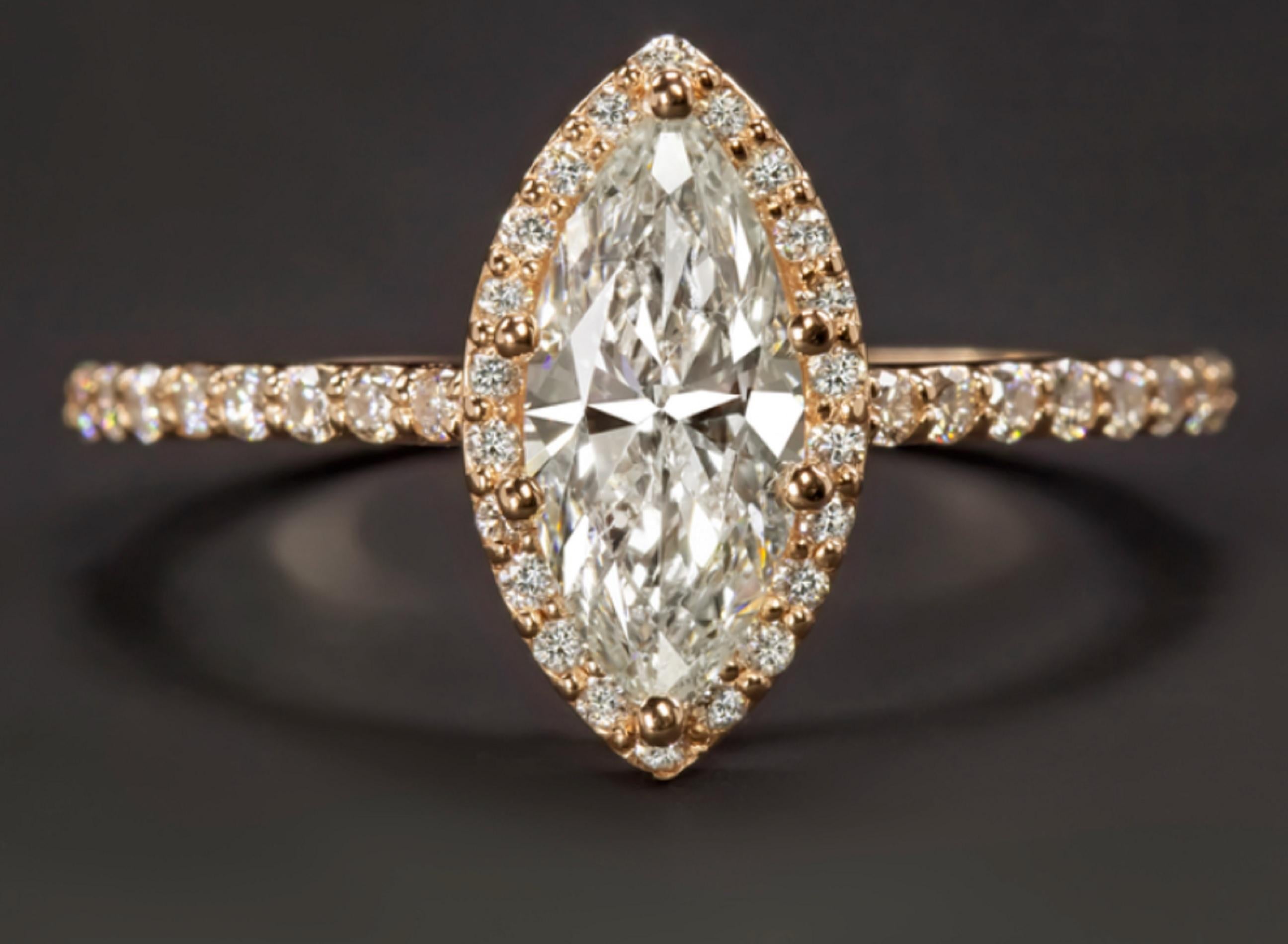 Cette magnifique bague de fiançailles est ornée d'un diamant blanc brillant de 1 carat de taille marquise, entouré d'un halo de diamants scintillants. Mesurant 13 mm de diamètre, l'anneau a une couverture fantastique, et un look glamour sur le doigt