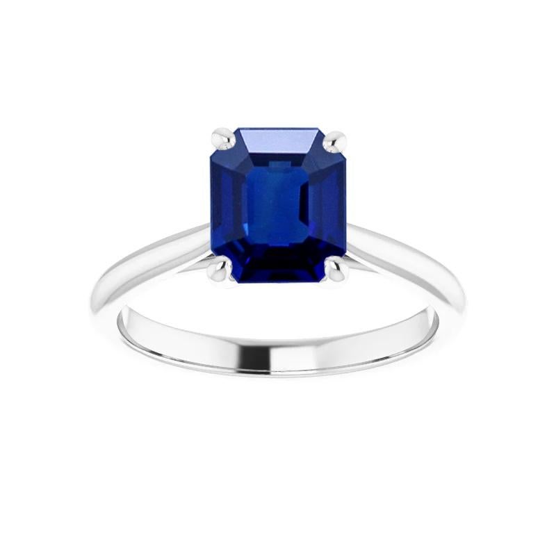 A classic solitaire engagement ring by Gem + Honey, set with a rectangular, step-cut, natural (no-heat, untreated) vivid blue Burma sapphire weighing well over one carat, set in Platinum 950. The sapphire accompanies a gemological certificate from