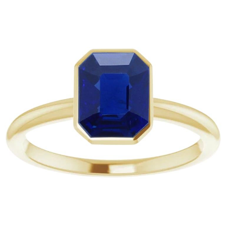 A  natural, no-heat (unheated) emerald-cut, bezel-set sapphire 18kt yellow gold ring by Gem + Honey. This chic ring is centered with a vivid blue Burmese sapphire. The sapphire weighs over 1.25 carats, and accompanies a gemological report from