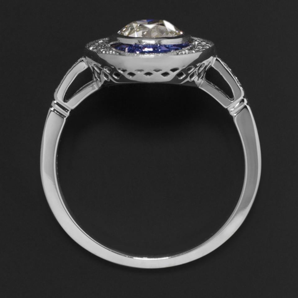 Beautiful and eye-catching diamond and sapphire ring features a vibrant 0.97 ct European cut diamond set in the center of an elegant Art Deco design. one of a kind vintage diamond. The 0.97 ct center diamond is exceptionally clean, graded VS1 for