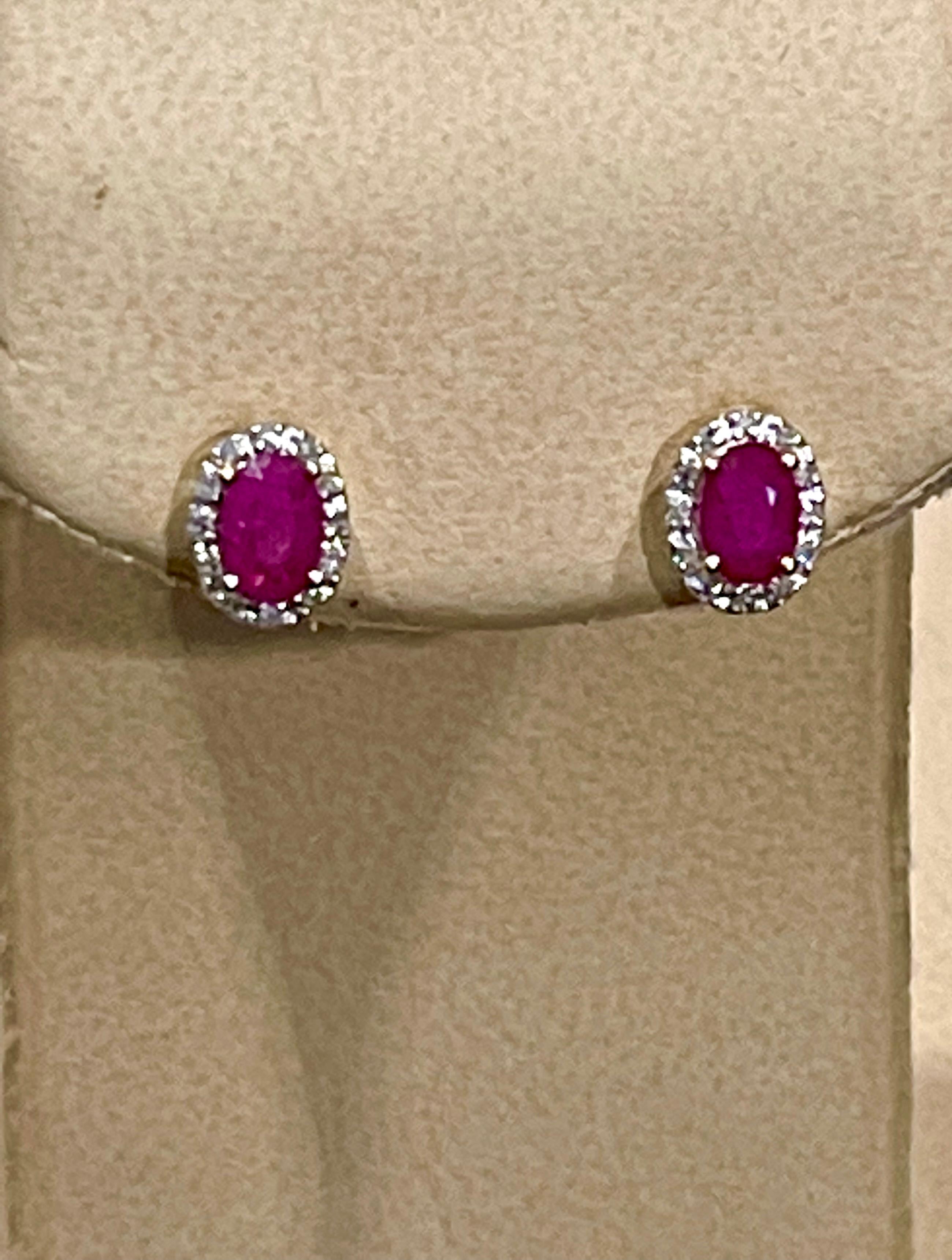 Cette luxueuse paire de boucles d'oreilles halo en rubis est conçue en or jaune 14 carats. Les rubis rouges ovales sont entourés d'un halo éblouissant de diamants ronds.
 Boucles d'oreilles avec clou en rubis naturel ovale en or jaune 14 carats
Deux