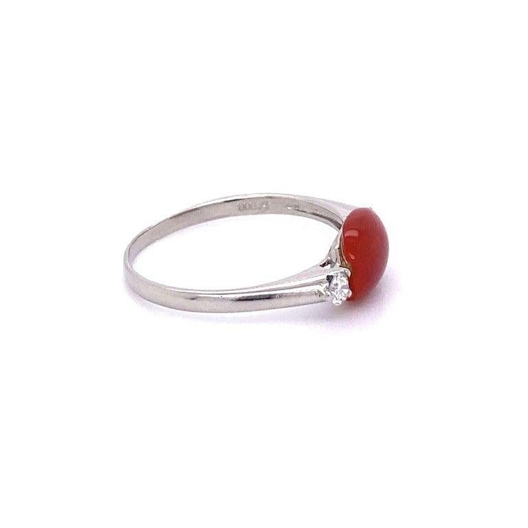 Simply Beautiful Platinum 3-Stone Coral and Diamond Ring, centering a Hand securely nestled 2.00 Carat oval Red Coral and a round Diamond on either side. The 2 Diamonds weighing approx. 0.11 total carat weight. Ring size: 6.75; we offer ring