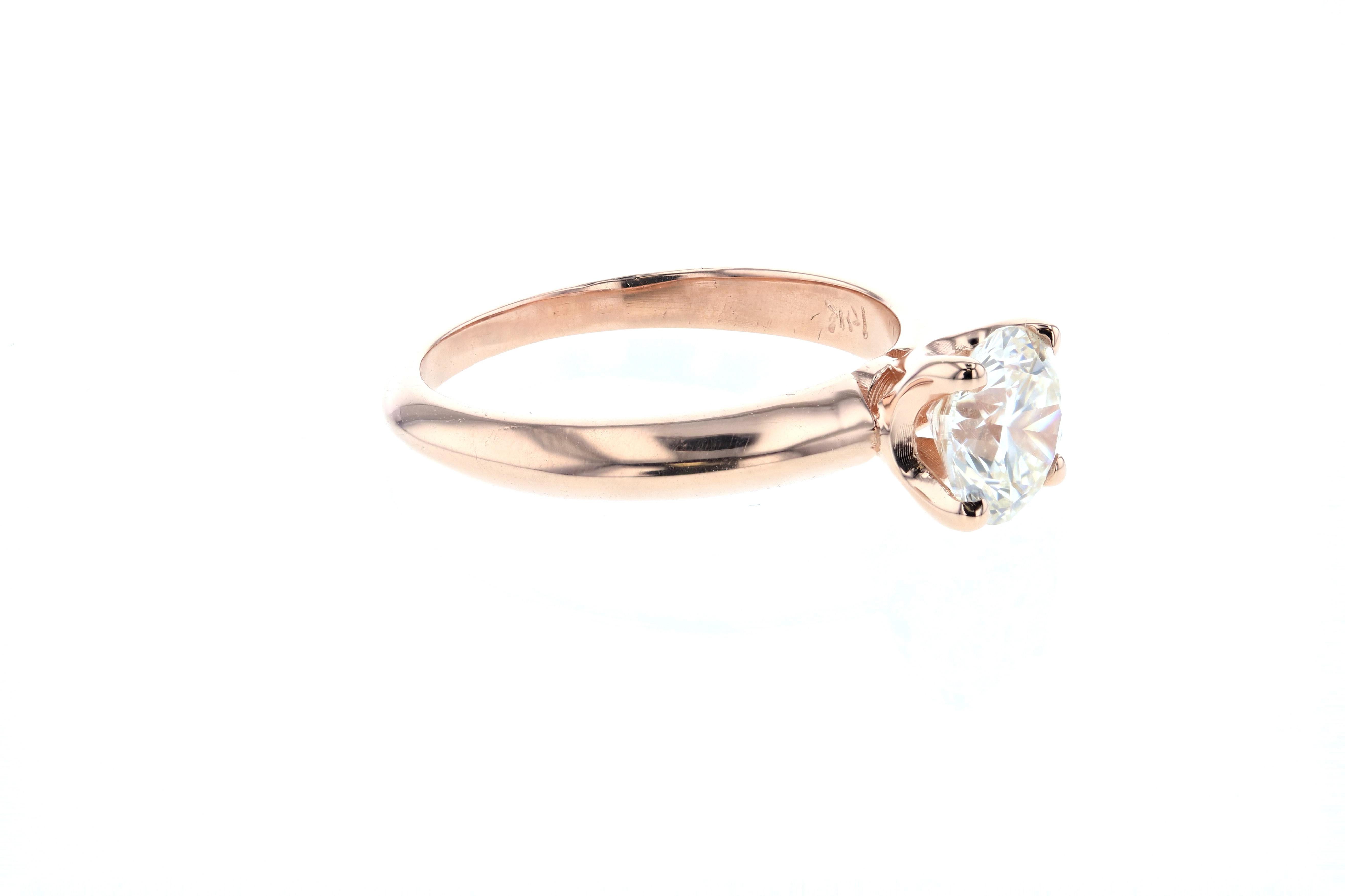 This beautiful rose gold solitaire engagement ring is crafted in 14k rose gold, and contains a Round Brilliant Cut Diamond (1.01 carats, I color, VS1 clarity). With a tapered knife edge setting and a four prong head on shank setting, this delicate