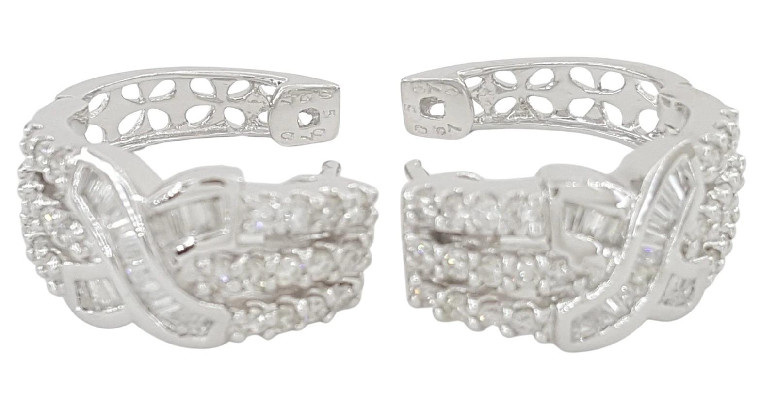 Elegant and distinctive, these 18K white gold hoop earrings feature a striking “X” crossover design adorned with a mix of round brilliant and baguette cut diamonds. The pair is set with a total of 81 natural diamonds — 46 round brilliant cuts and 35