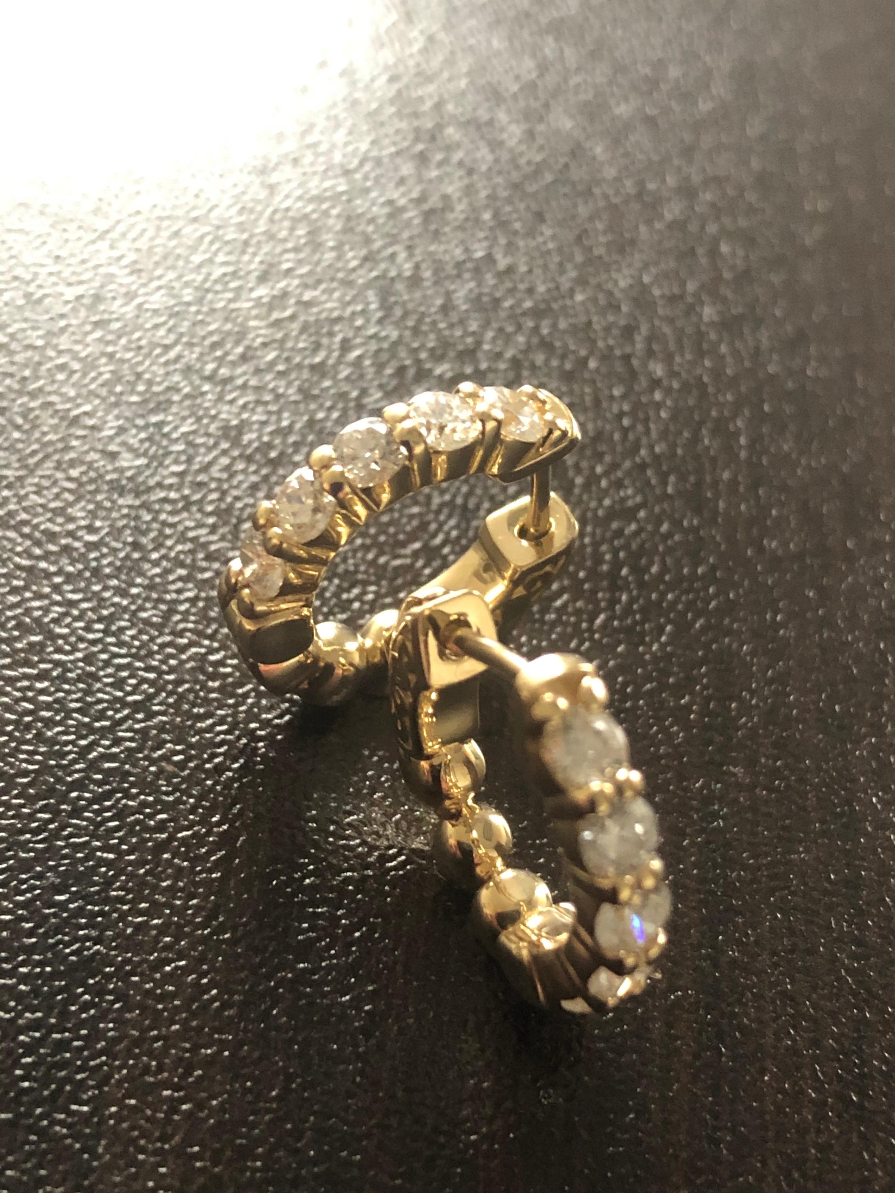 Diamond huggies set in 14K yellow gold. The total weight of the huggies hoop is 1 carat exact. The earrings are set with 10 stones on the outside each weighing 0.10 carats. The color of the stones are G, the clarity is SI1. Huggies are available in