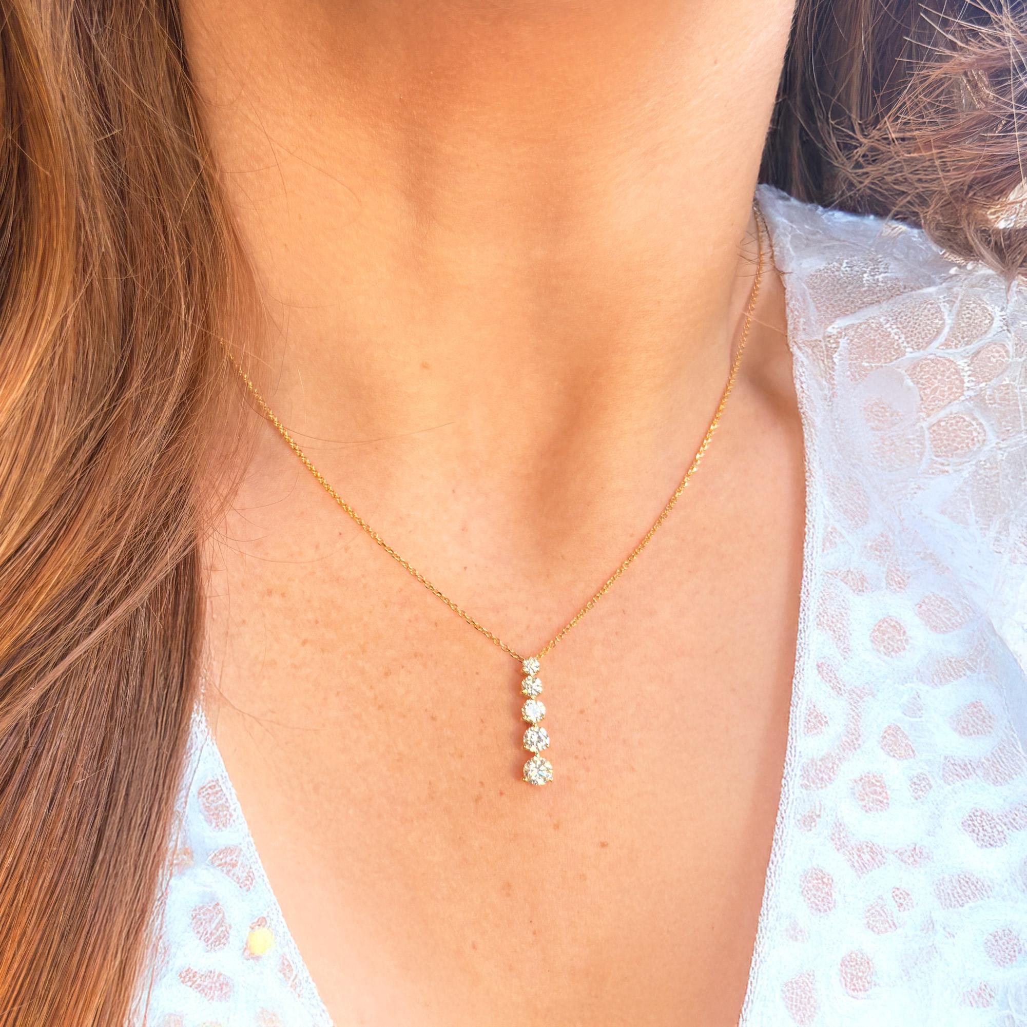 Questa squisita collana con pendente mette in mostra cinque diamanti naturali taglio rotondo brillante, graziosamente disposti in un design verticale graduato. Ogni diamante è sapientemente incastonato nell'oro 14K, creando un pezzo senza tempo che