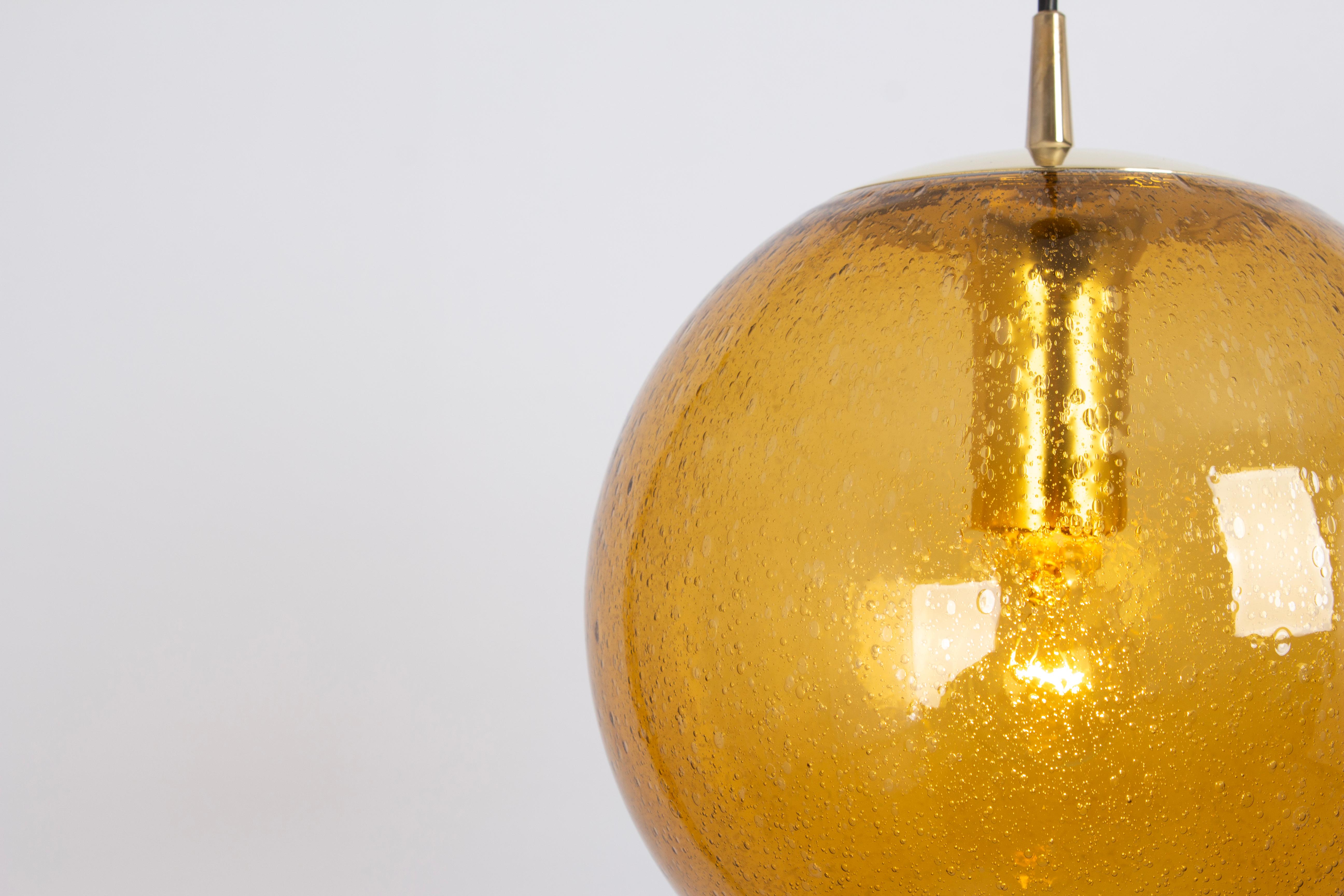 A special round dark yellow glass pendant designed by Peill & Putzler, manufactured in Germany, circa 1970s.
High quality and in very good condition. Cleaned, well-wired, and ready to use. 
Each fixture requires a 1 x E27 Standard bulb 
Light bulbs