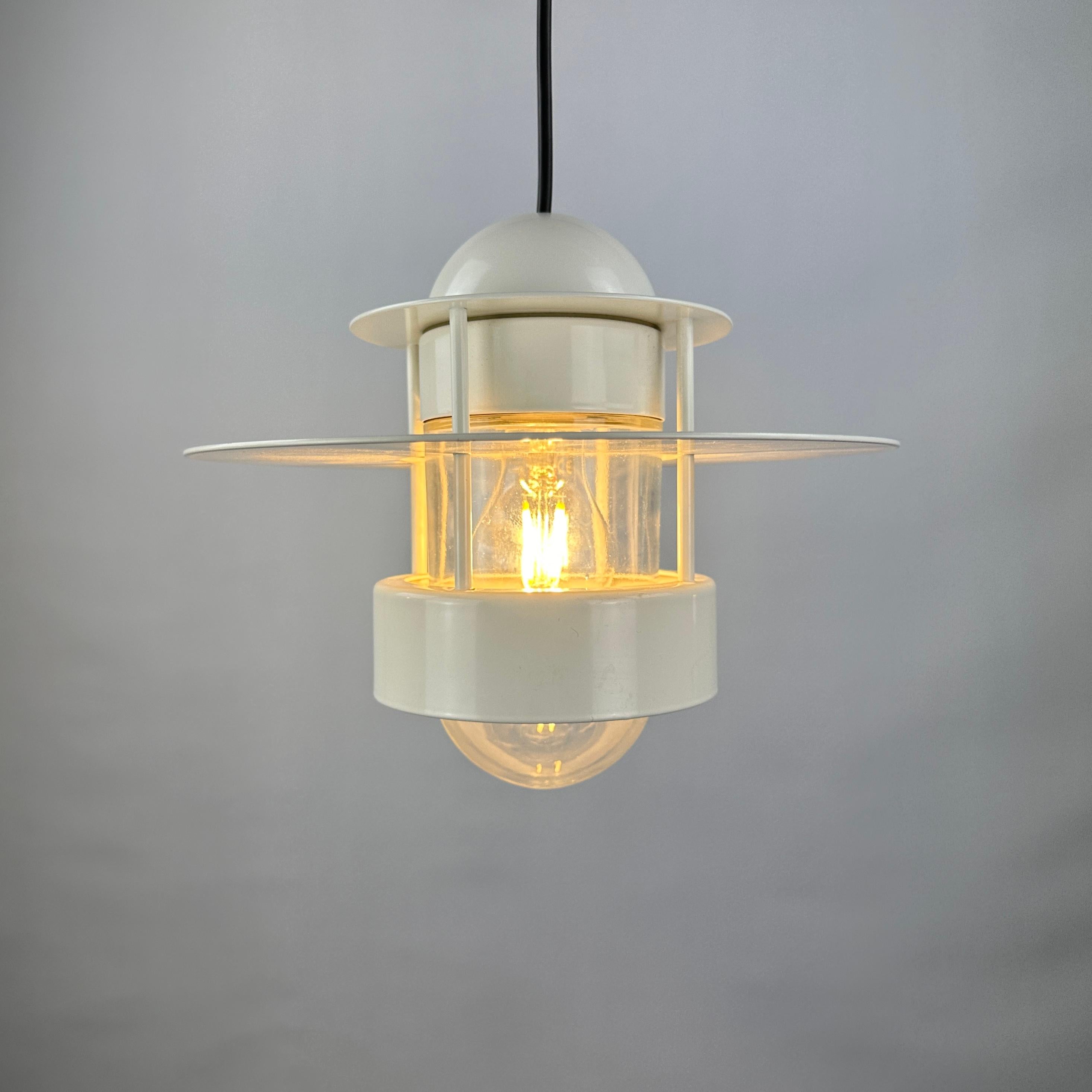 Cette lampe suspendue en forme d'OVNI a été conçue par Jens Møller Jensen pour Louis Poulsen en 1963. Ce modèle s'appelle Albertslund, parfois nommé Orbiter mais c'est le plus grand modèle. Elle est en métal et a un abat-jour en verre à l'intérieur,