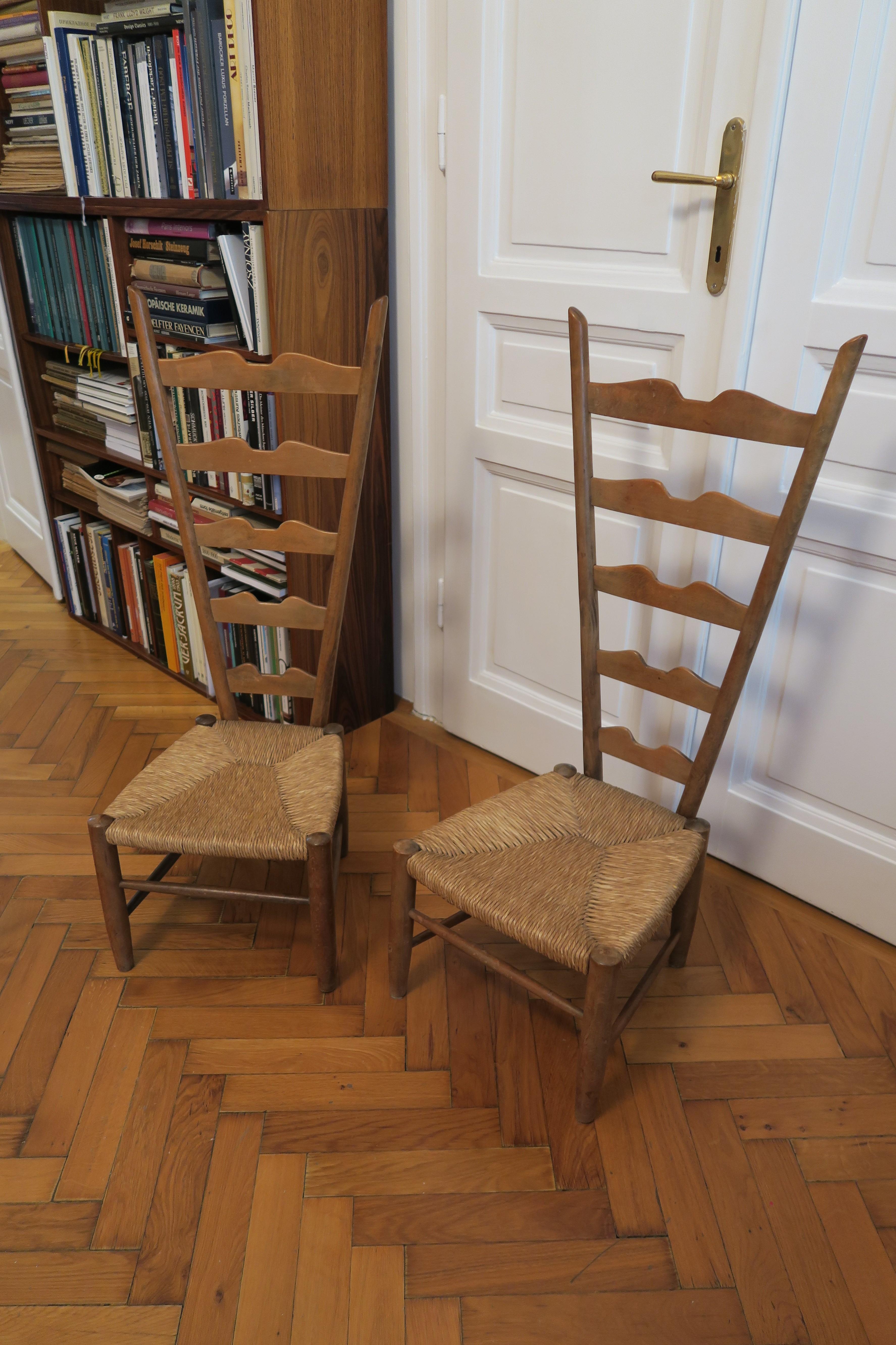 Handsome pair of Italian fireside ladderback chairs designed by Gio Ponti for Casa e Giardino. They are in fabulous original condition with a lovely age patina to the wood and the rush seats. No outstanding flaws. Three of the plugs which cover