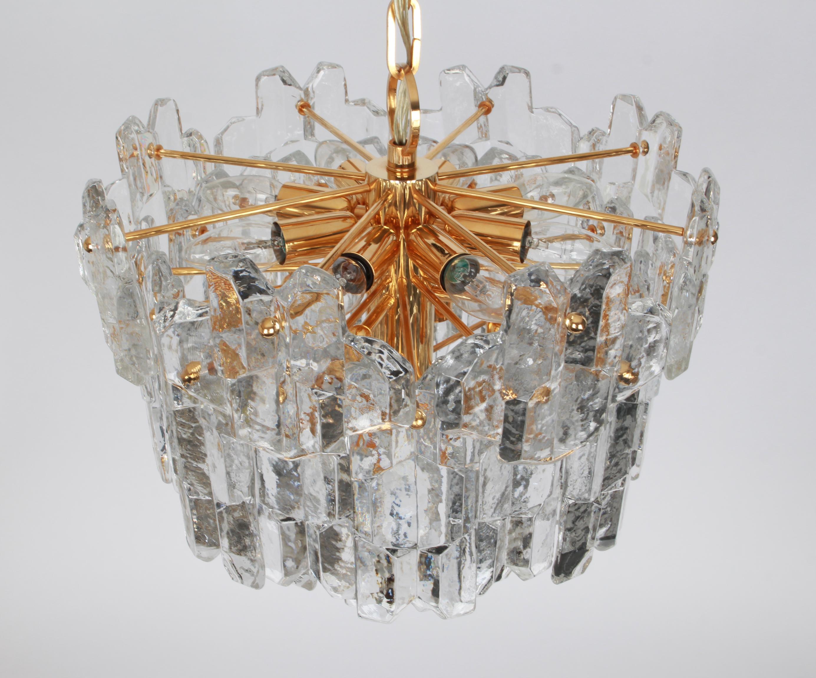 Wonderful gilt brass chandelier comprises crystal Murano glass pieces on a gilded brass frame. It’s made by Kalmar (Series: Palazzo), Austria, manufactured, circa 1970-1979.

4 tiers structure gathering many structured glasses, beautifully