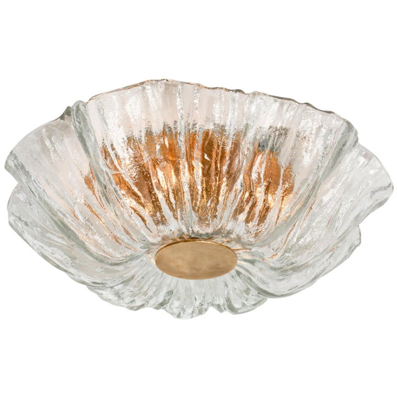 One of two high quality modern textured ice glass flushmounts by Kaiser, circa 1965.
This flushmounts are featuring a huge round hand blown flower glass dish giving the piece a heavy ice appearance which refracts the light, filling a room with a