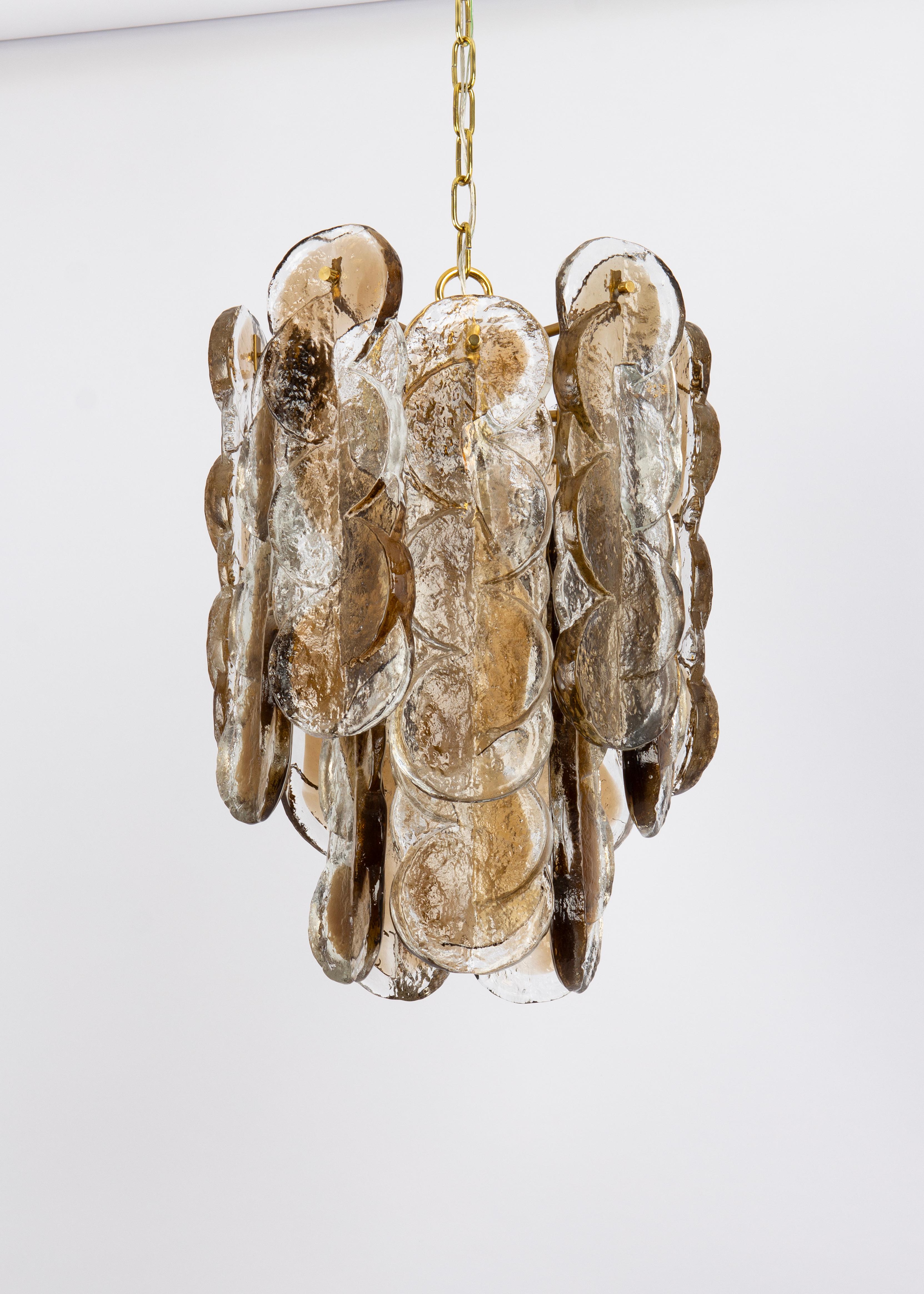 Lampadario in vetro di Murano di Kalmar, anni '70.
Vetro da ghiaccio fumè, pannelli di cristallo trasparente ritorto con una striscia color oro chiaro e ambra.

Di alta qualità e in ottime condizioni. 

L'apparecchio richiede 5 lampadine E14 piccole