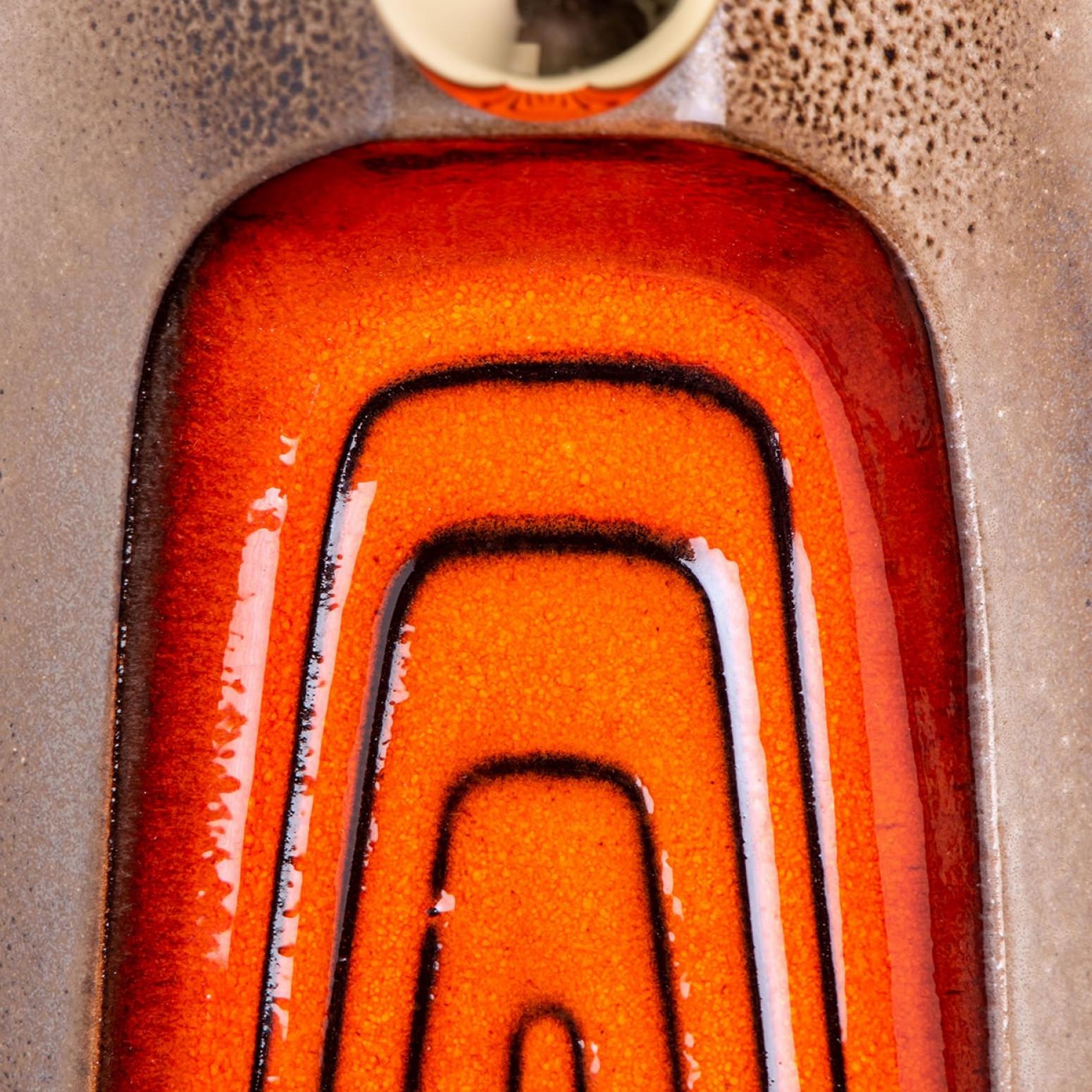 Applique/apparecchiature in ceramica arancione a forma di rettangolo, Germania, anni '70. La base della lampada è rettangolare e sopra ci sono delle bellissime volute in ceramica.

Queste luci hanno una forma insolita. In questo modo è possibile