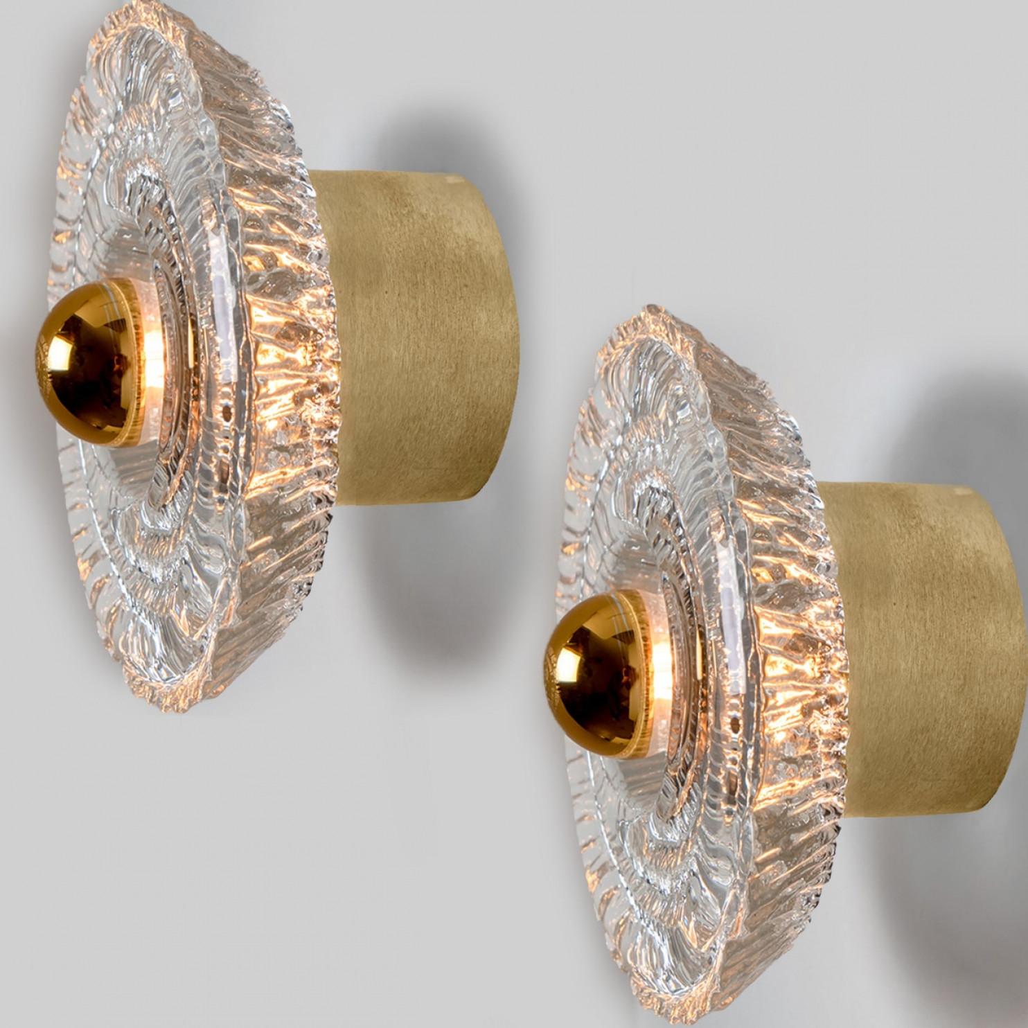Four beautiful mid-20th century wall lights by Peill & Putzler. Made around 1970 in Germany, Europe. Featuring a large clear glass shade with gold around it. The light illuminates wonderful.

The lights can also be used as flush mounts.

Please note