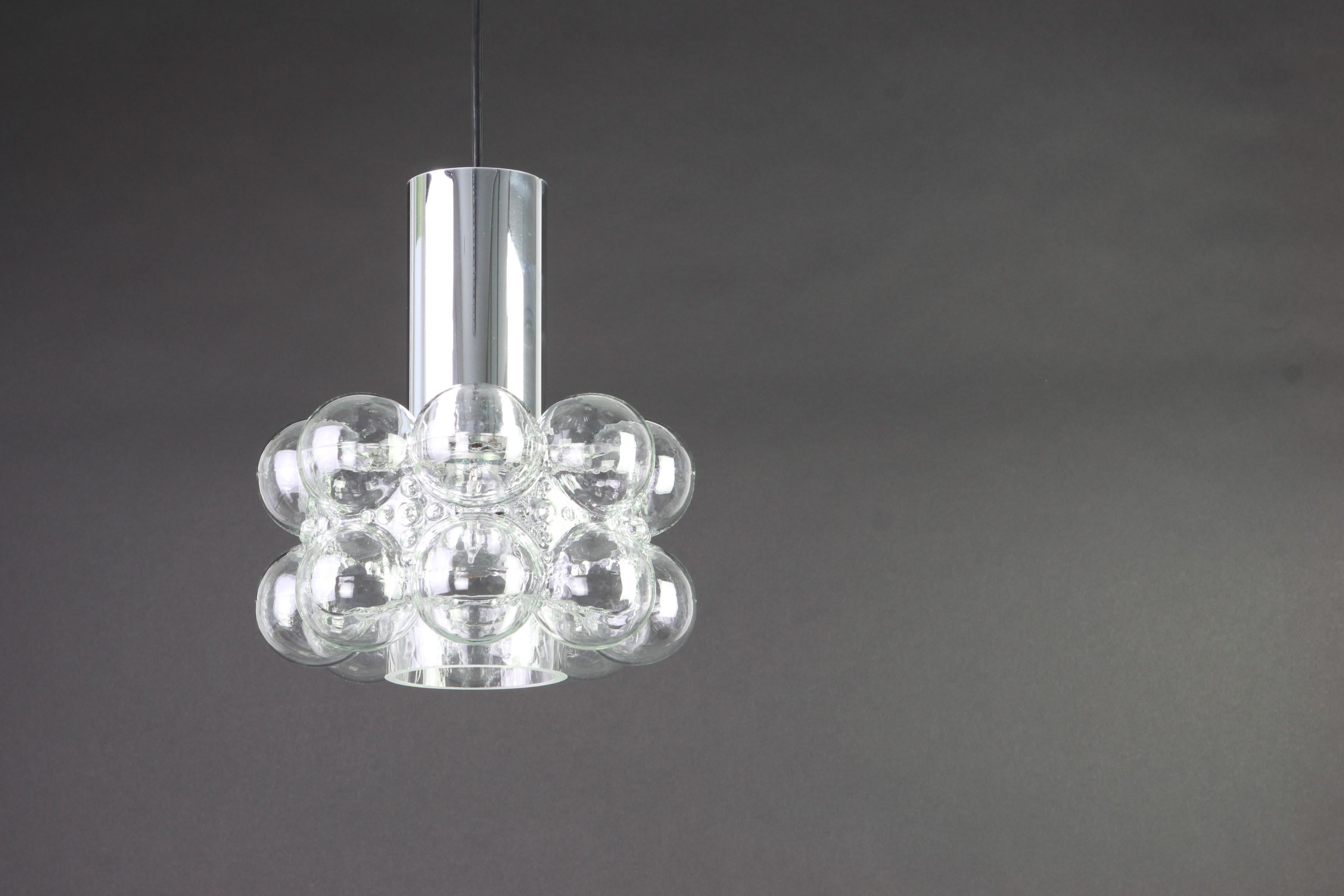 1 de 2 pendentifs ronds en verre bullé conçus par Helena Tynell pour Limburg, fabriqués en Allemagne, vers les années 1970.

Douilles : nécessite 1 ampoule standard E27 de 100W max chacune et compatible avec les normes US/UK/ etc.
La tige de