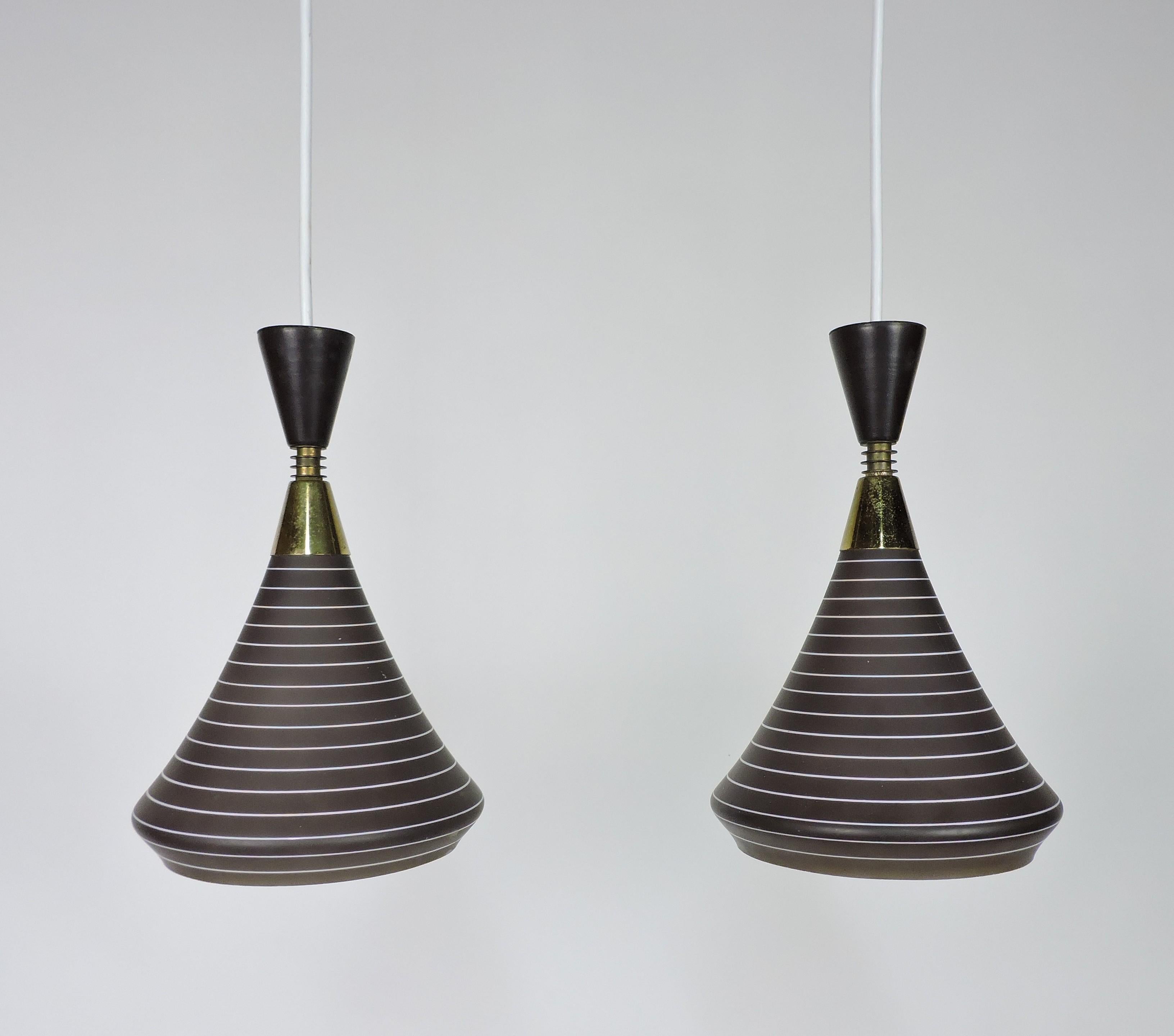 Very cool and unique pair of mid century modern 1950s pendant lamps. These lamps have cone shaped cased glass shades with etched stripes and brass accents. An inverse metal cone tops each shade for a classical mid century look. These have all new