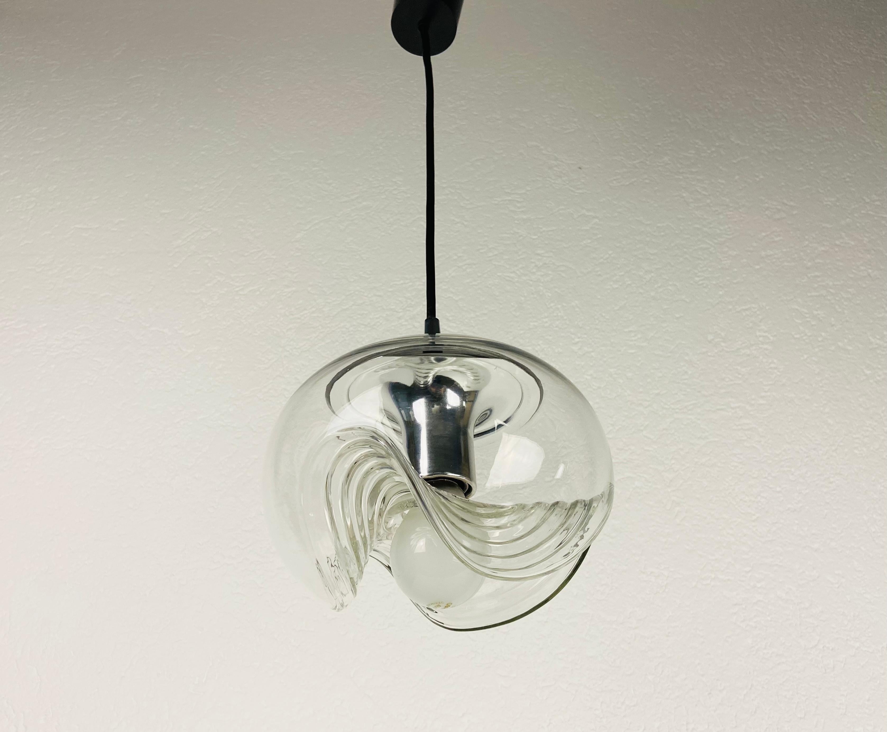 Lampe suspendue ronde de Koch & Lowy pour Peill et Putzler, fabriquée en Allemagne dans les années 1960. Il est fascinant avec son beau verre transparent. La lampe a un design de l'ère spatiale.

La lampe nécessite une ampoule E27. Très bon état