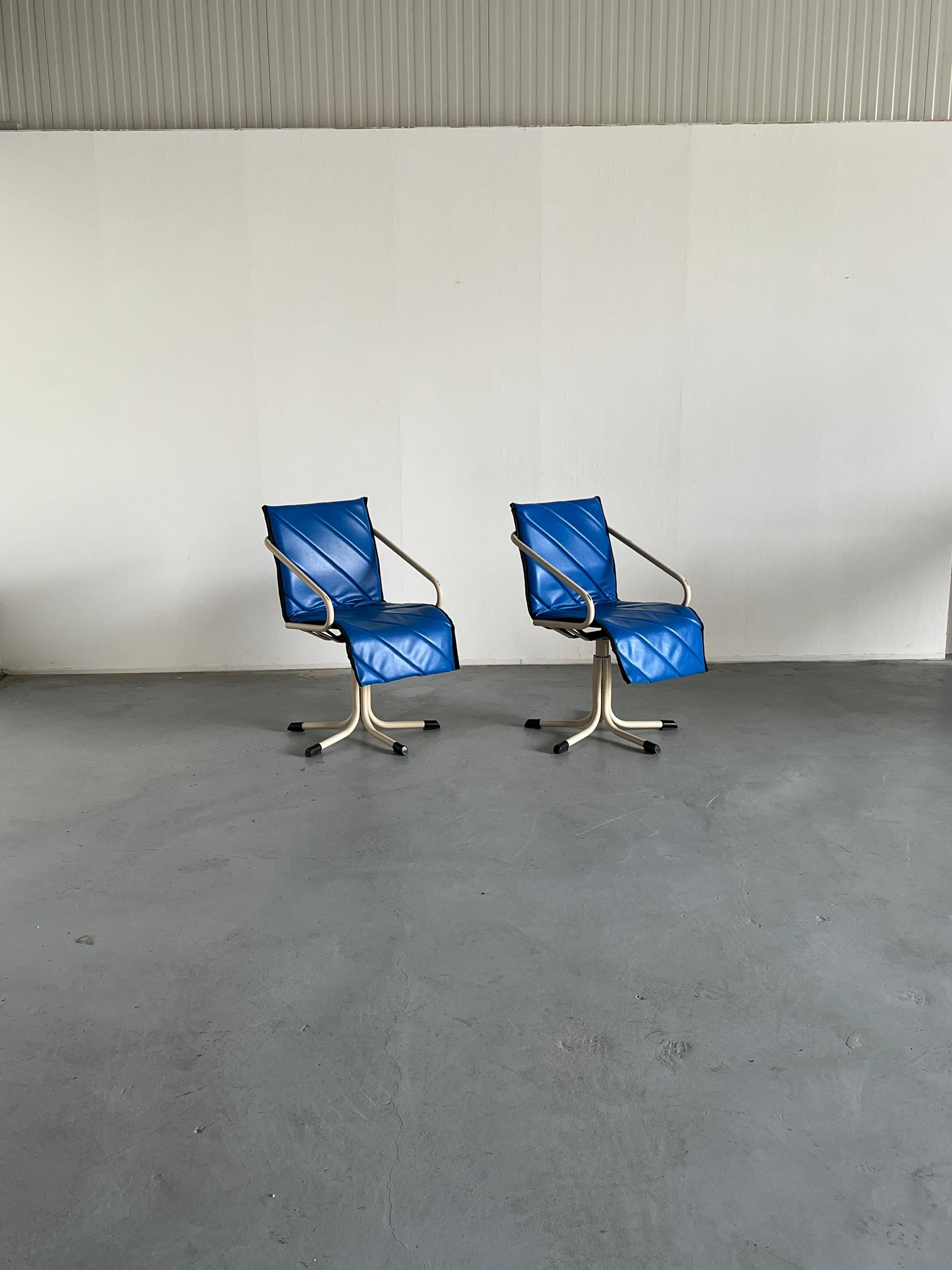 Two unique German space age or atomic age swivel armchairs, in blue faux leather seat and white metal base. Produced by Müster.

Well preserved, with some expected signs of age, mostly surface scratches on the metal parts - mostly visible on the