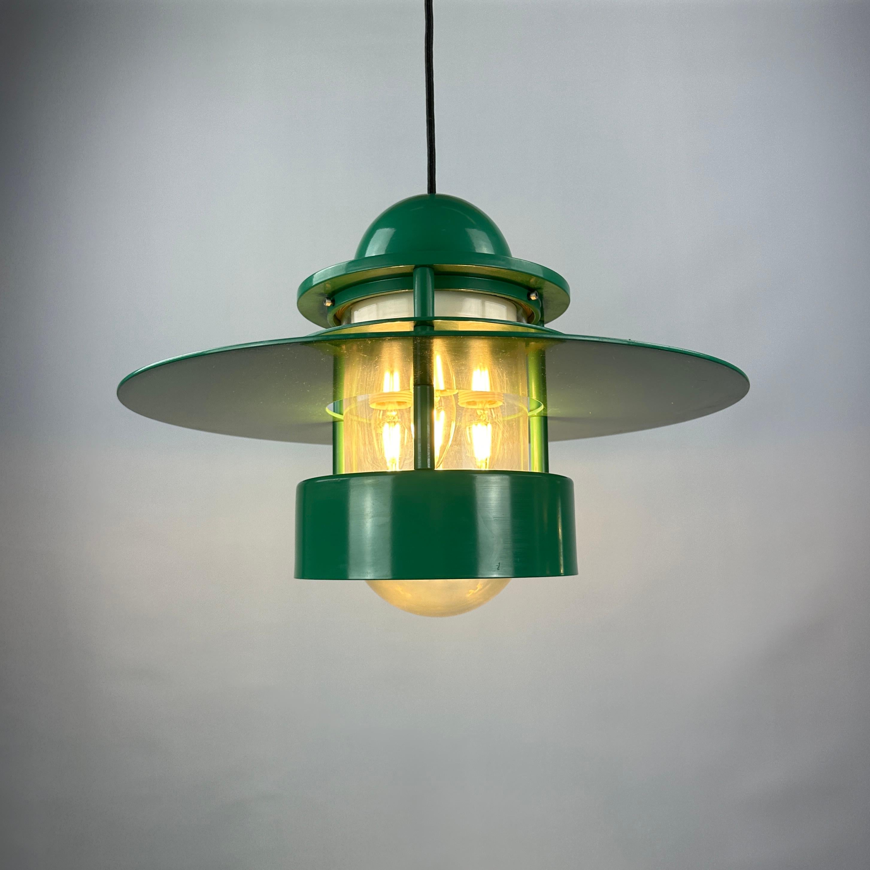 These cool large UFO shaped pendant lamp is designed by Jens Møller Jensen for Louis Poulsen in 1963. This model is called Orbiter and is the largest model of this serie. This round lampshade is made of green enamelled metal and has a clear plastic