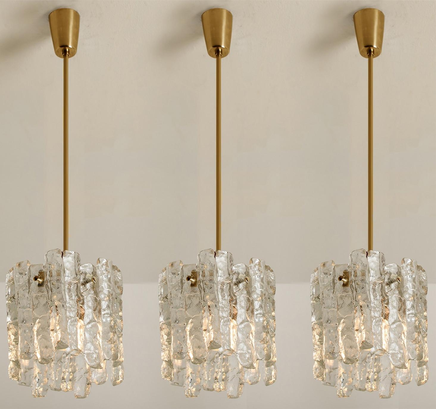 Beautiful and elegant modern pendant lights, manufactured by Kalmar, Austria in the 1970s.  High end simplistic design. Each light has brass sockets and one layer of extremely stylish textured solid ice glass sheets with brass screws.

Pleas notice